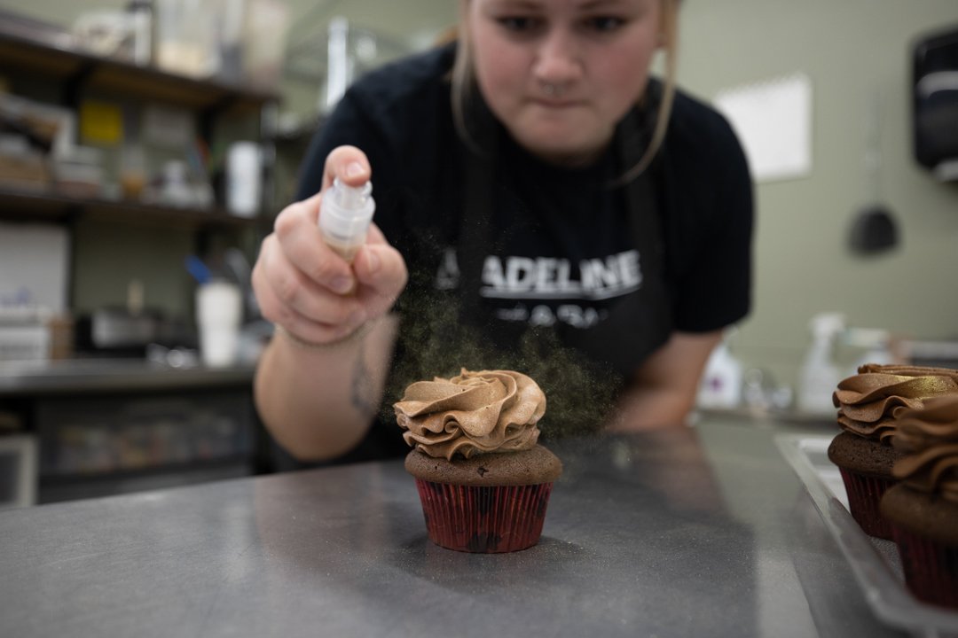female cook spraying gold dust onto a cupcake, shot by commercial photographer Corey Rourke

