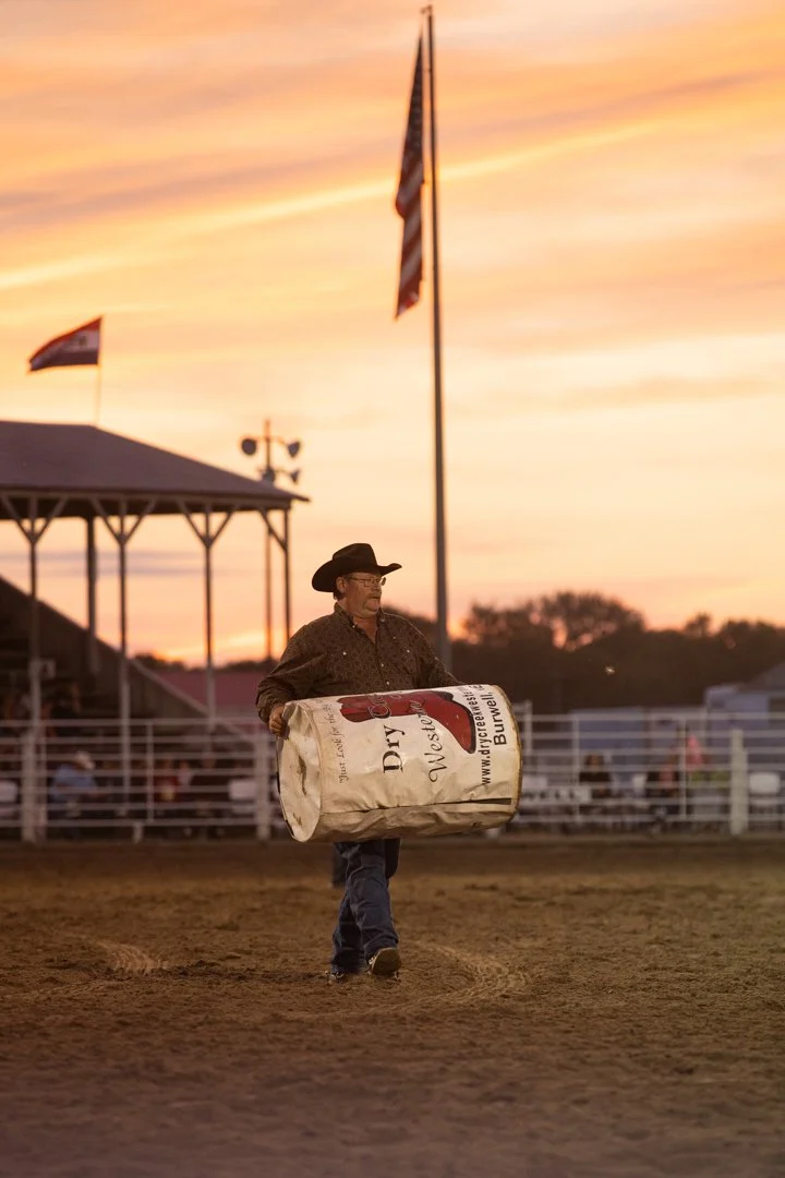 cowboy carrying a barrel in the rodeo arena, shot by commercial photographer Corey Rourke

