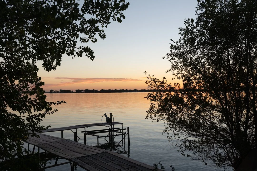 sunset image of dock with trees in foreground and sunset in background, shot by commercial photographer Corey Rourke
