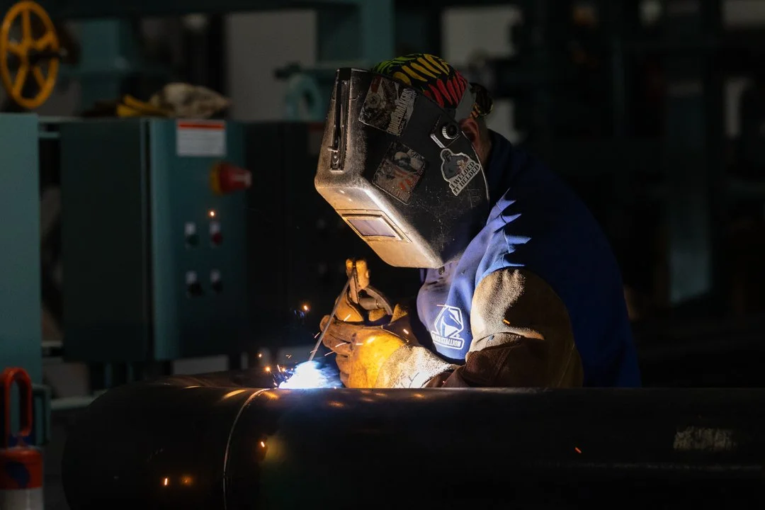 industrial welder is working with sparks around a pipe. Shot by commercial photographer Corey Rourke
