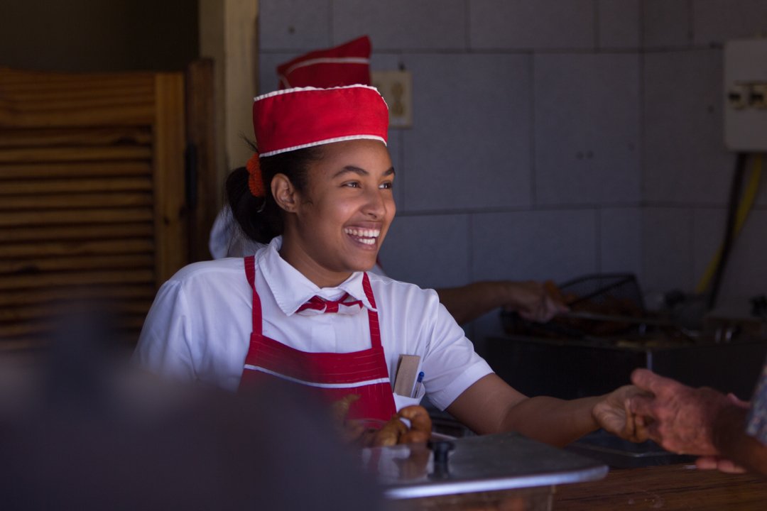 woman smiling and handing customer food

