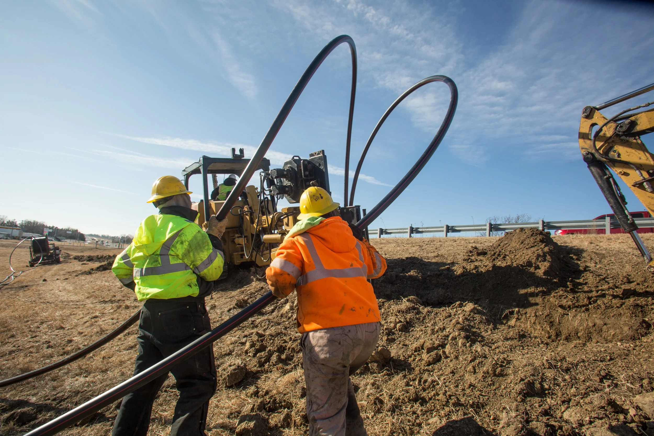 construction workers pushing electrical tubes into ground, shot by commercial photographer Corey Rourke

