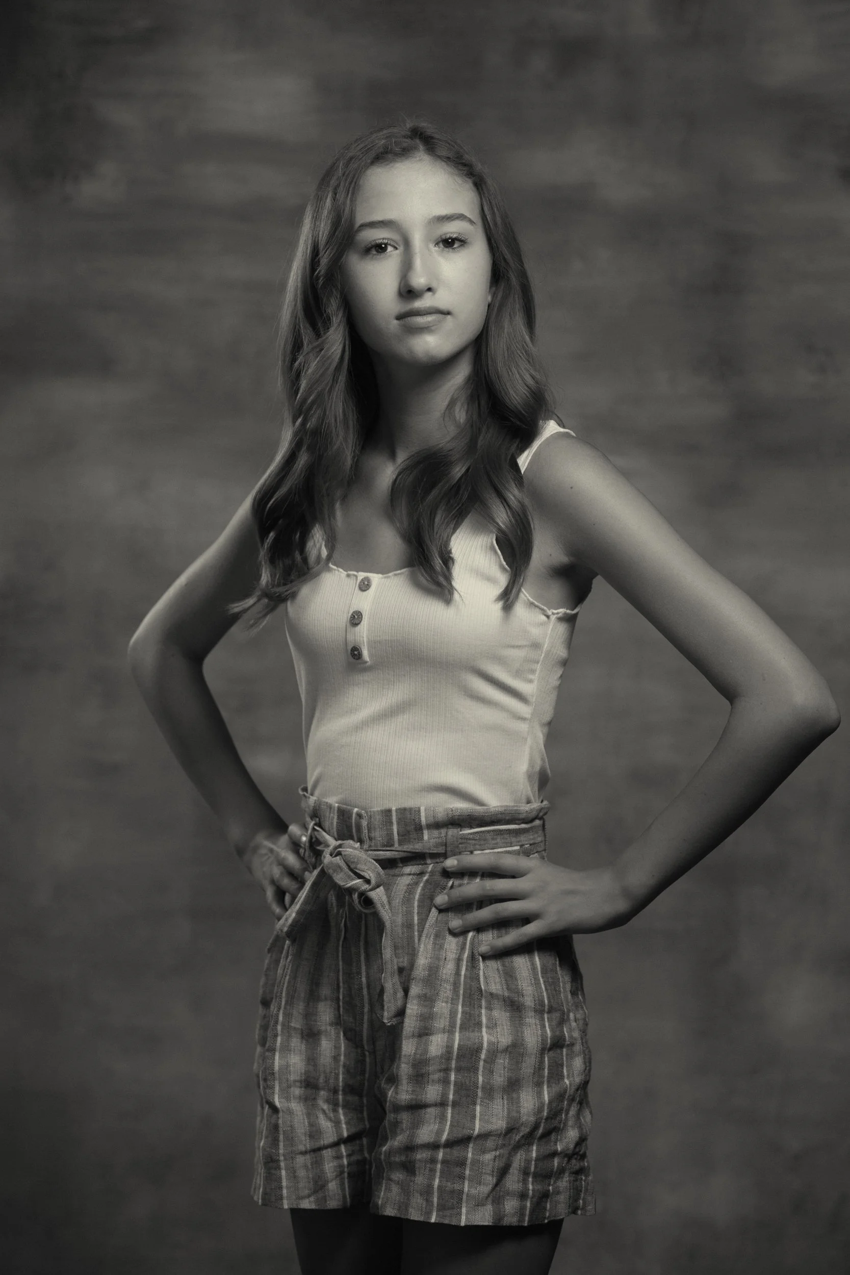 black and white studio portrait of tween with her hands on her hips, shot by commercial photographer Corey Rourke
