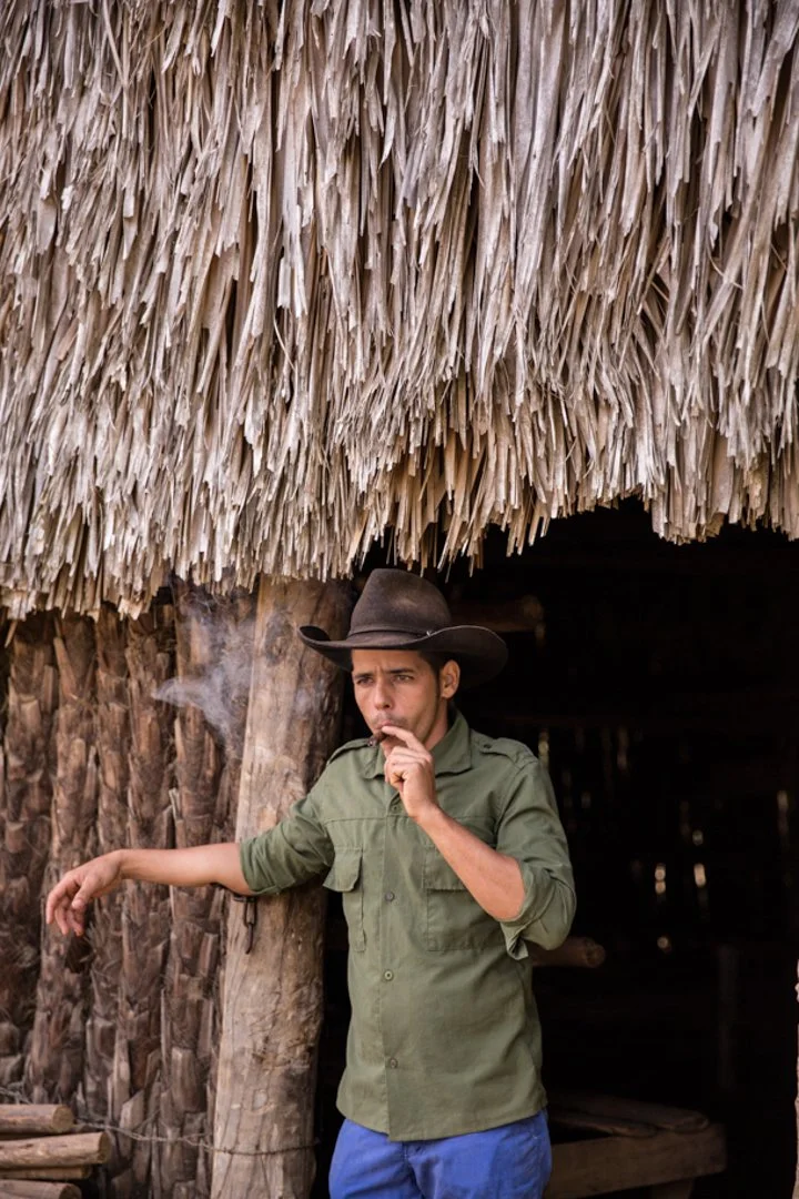 plantation farmer indoor way of hut smoking cigar
