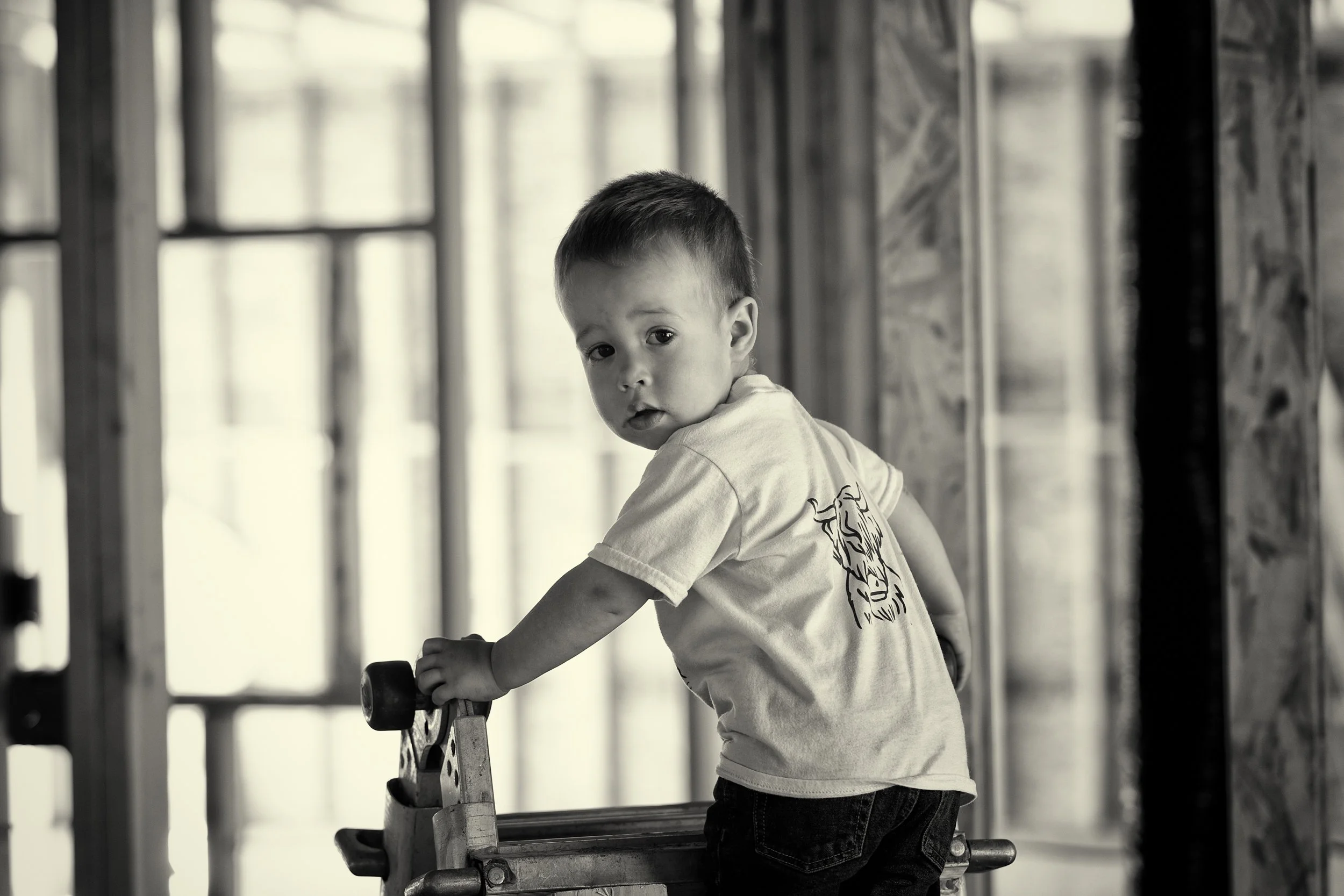 black & white image of a child on a ladder at a construction site. 