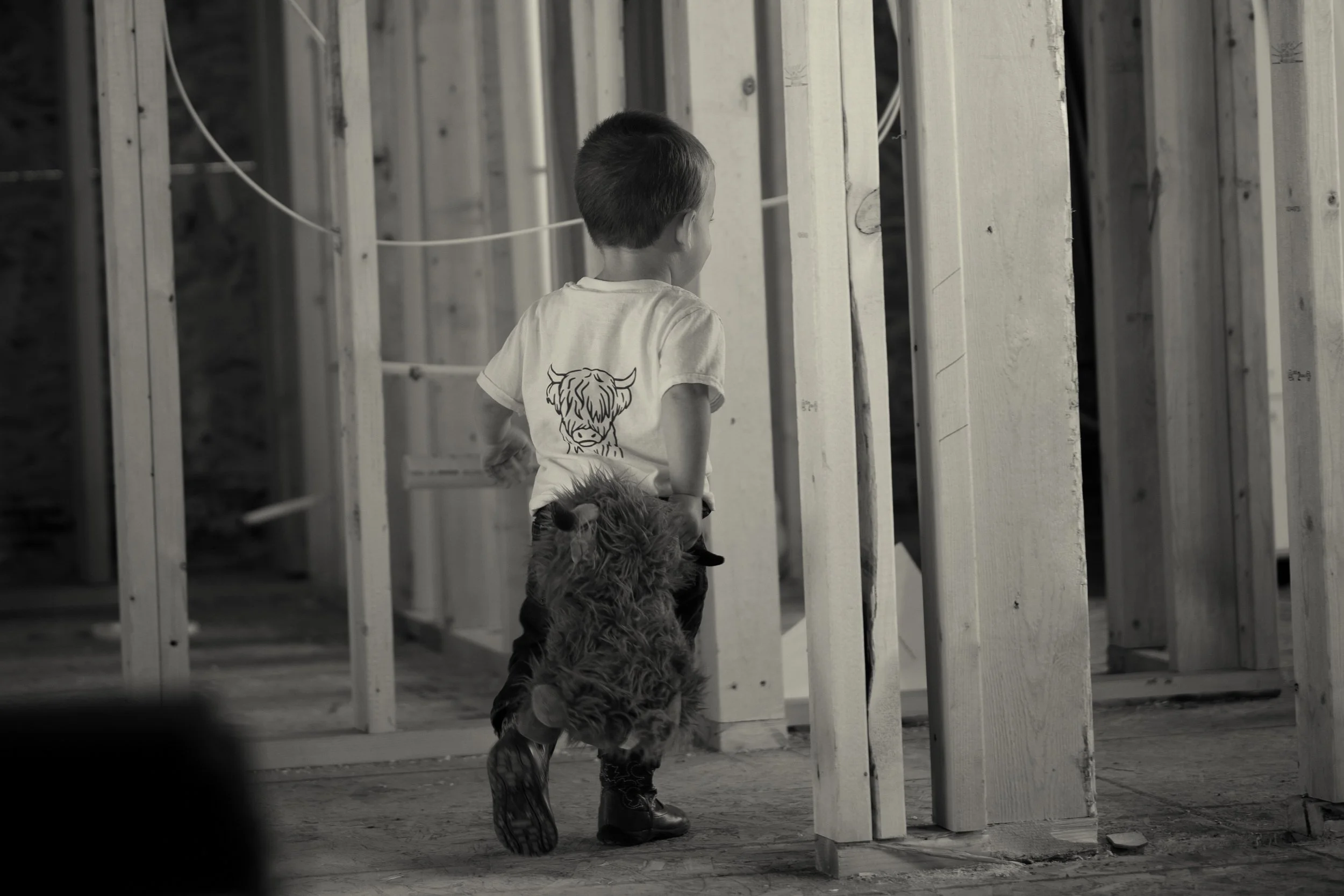 black & white image of child walking through construction beams