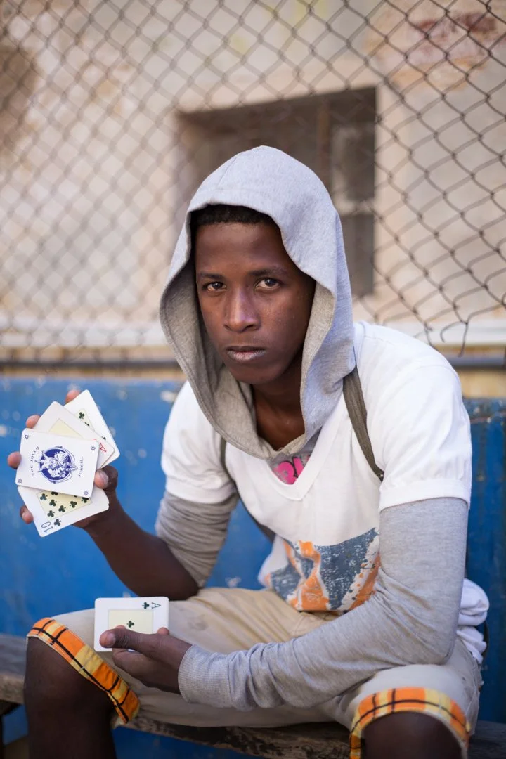 teenager wearing hood holding playing cards in right hand
