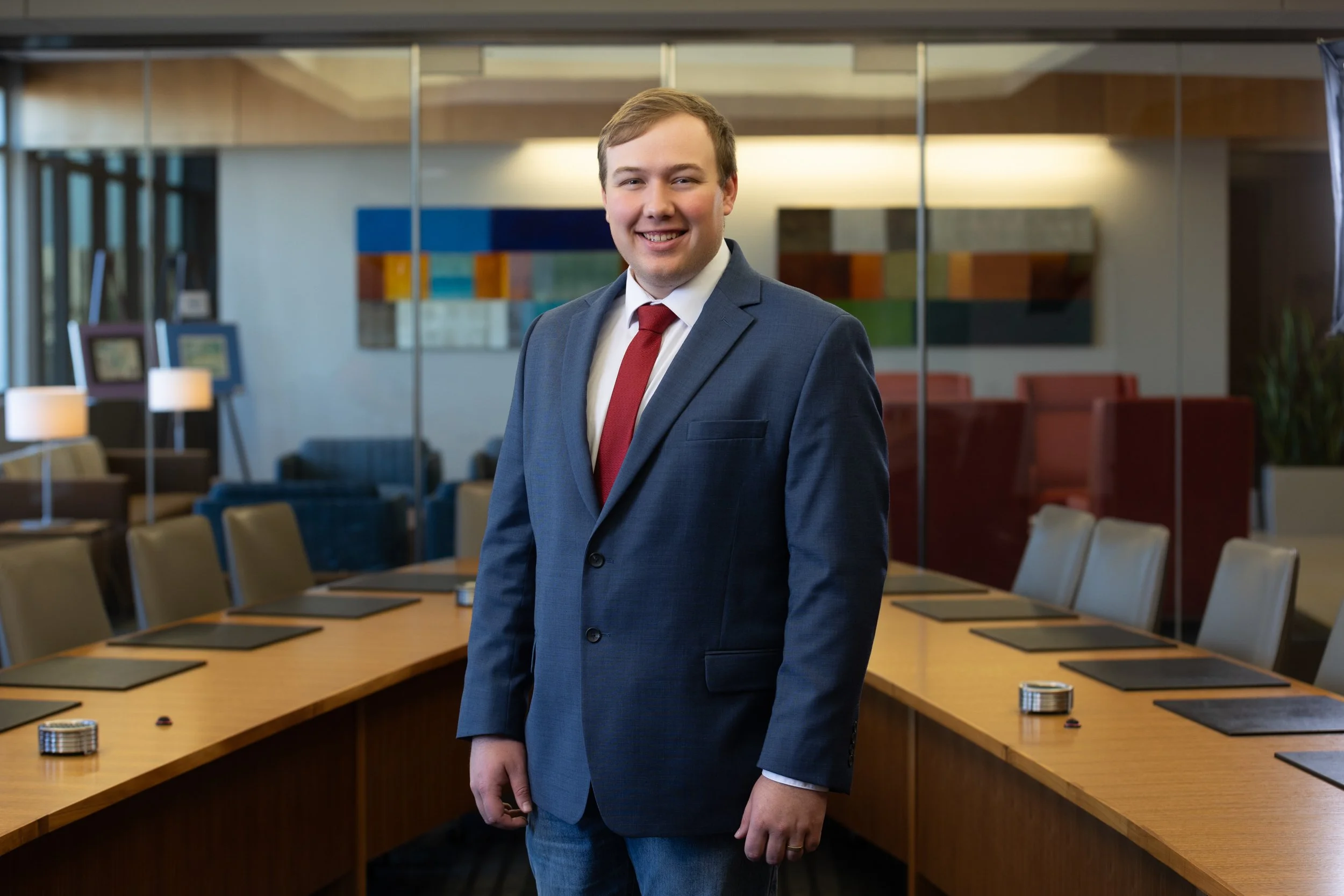 Corporate headshot of man in in a blue suit in a conference room