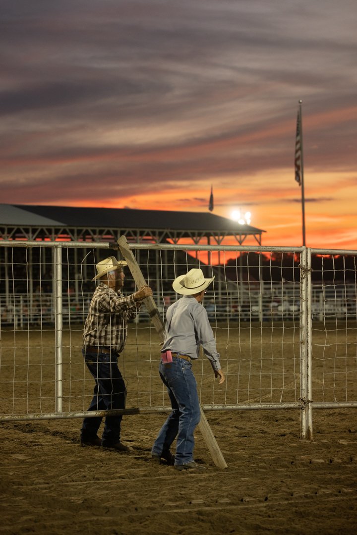 cowboys putting up fence in rodeo arena at sunset, shot by commercial photographer Corey Rourke

