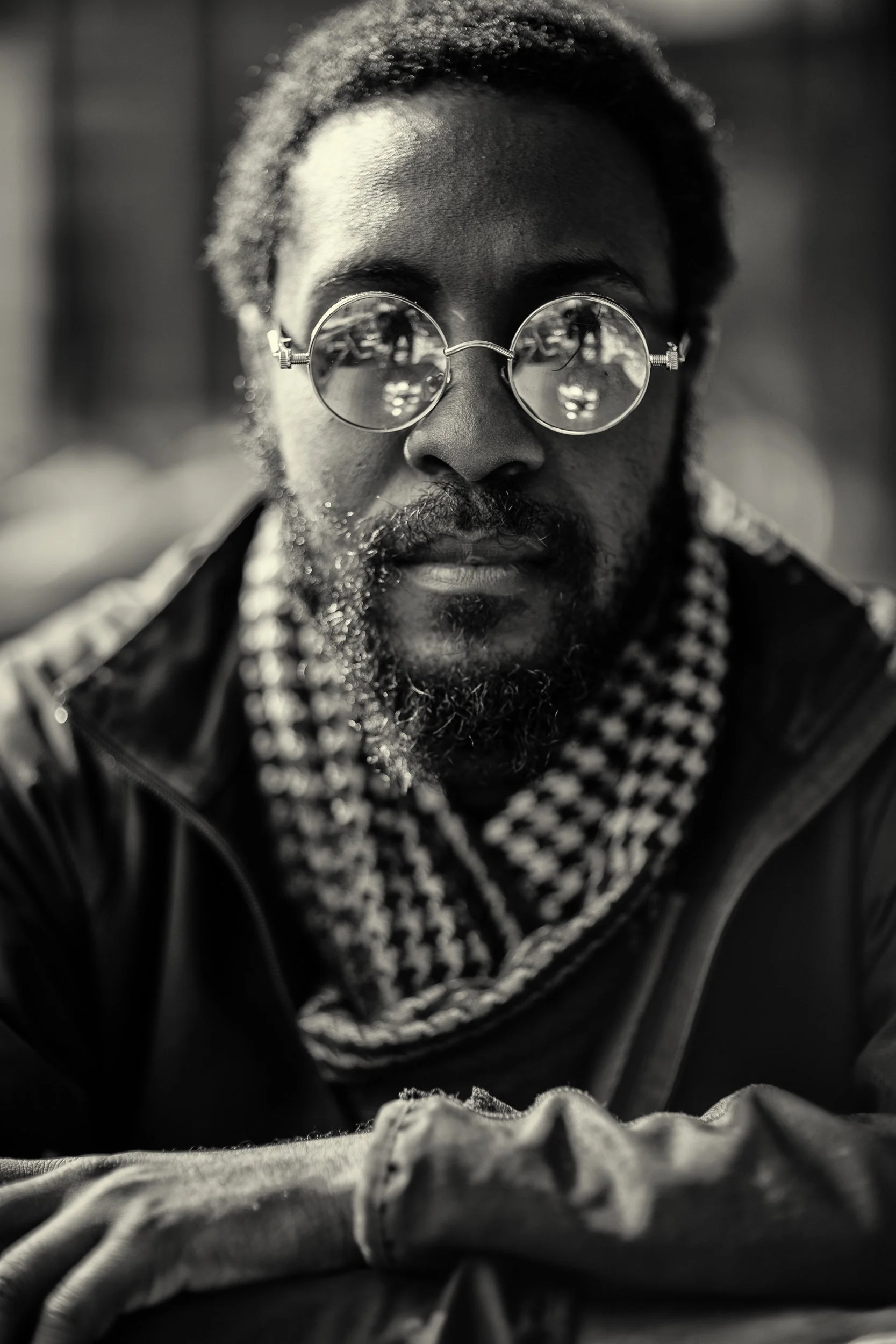 black and white close up of man leaning in on table.  sun glasses have reflection of table and coffee, shot by commercial photographer Corey Rourke

