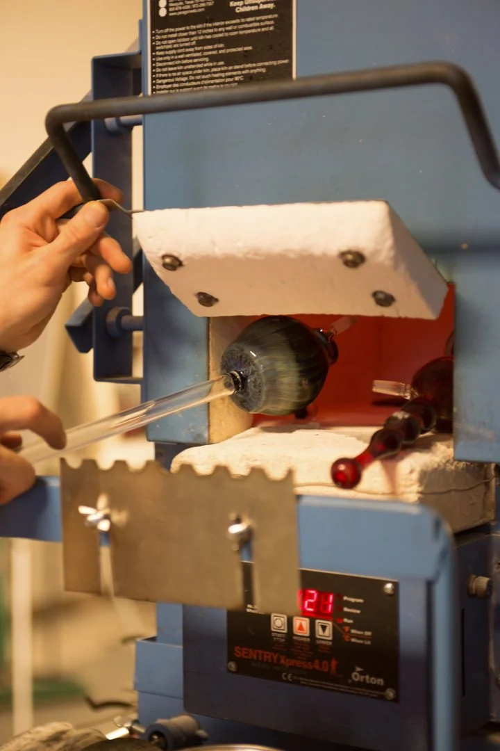 glass blower putting pipe in kiln, shot by commercial photographer Corey Rourke
 