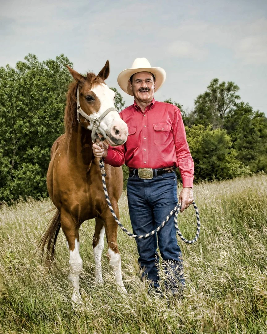 portrait of cowboy wearing a redshirt and cowboy hat with his horse in a field, shot by commercial photographer Corey Rourke
