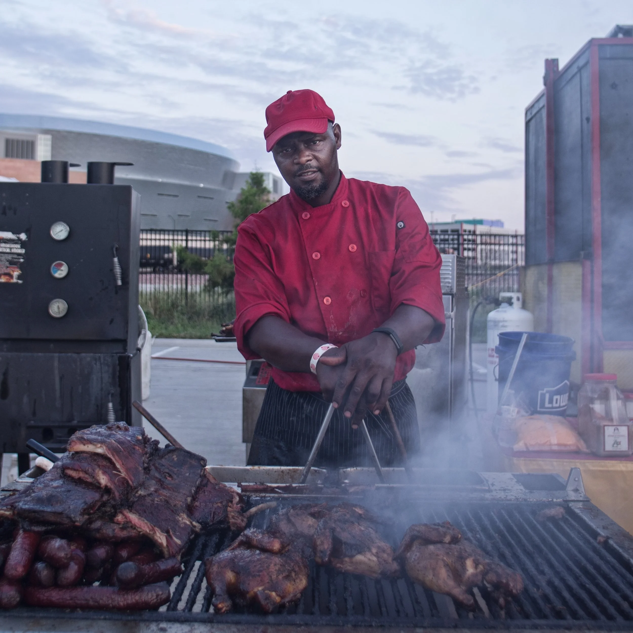 pit master leaning in on his tongs in front of the grill full of meat, shot by commercial photographer Corey Rourke

