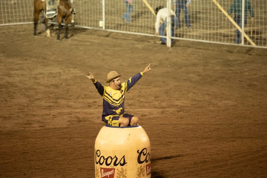 rodeo clown sitting on top of a barrel with his hands in the air, shot by commercial photographer Corey Rourke

