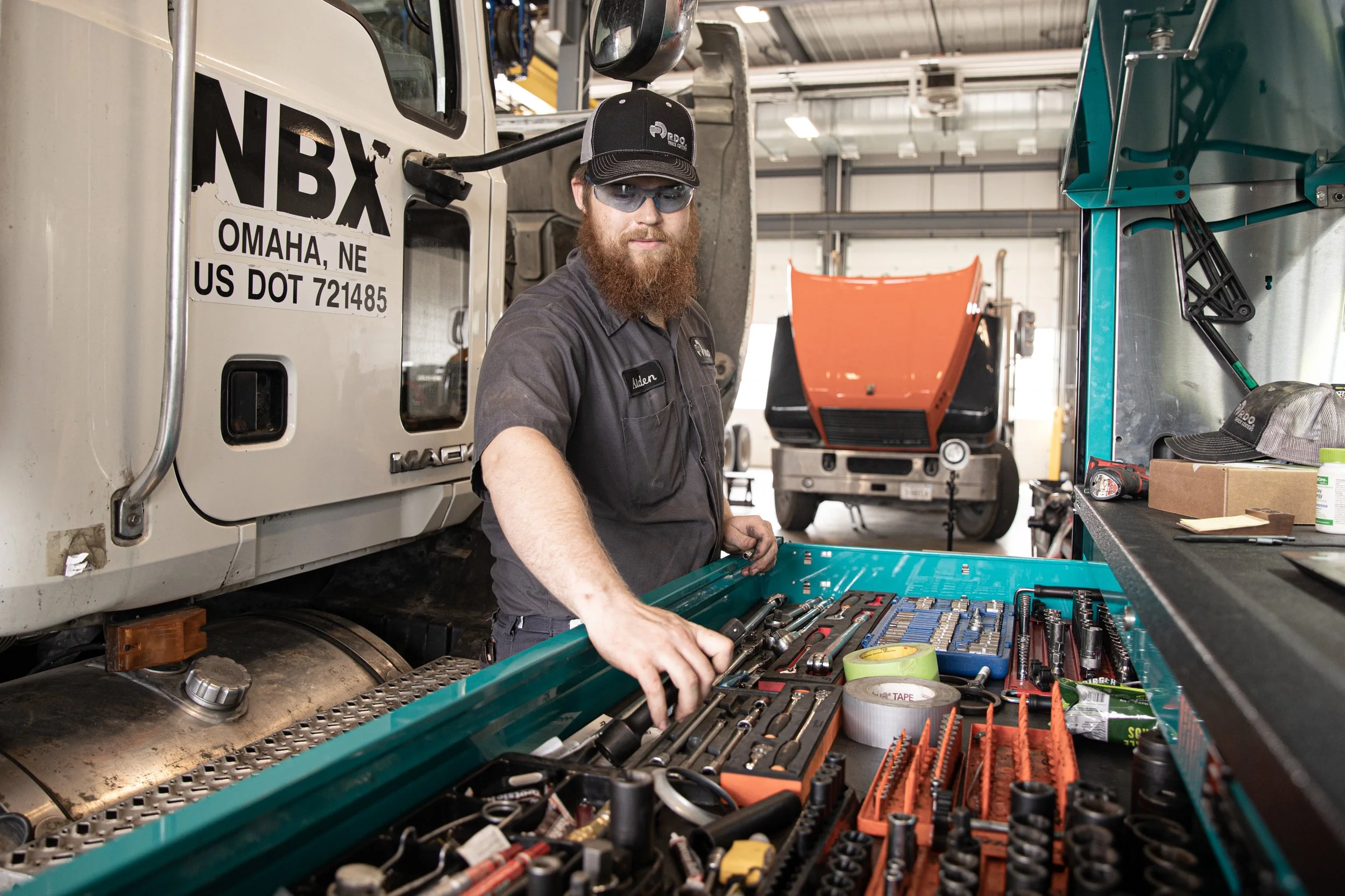 image of mechanic grabbing his tools with a semi truck in the background, shot by commercial photographer Corey Rourke

