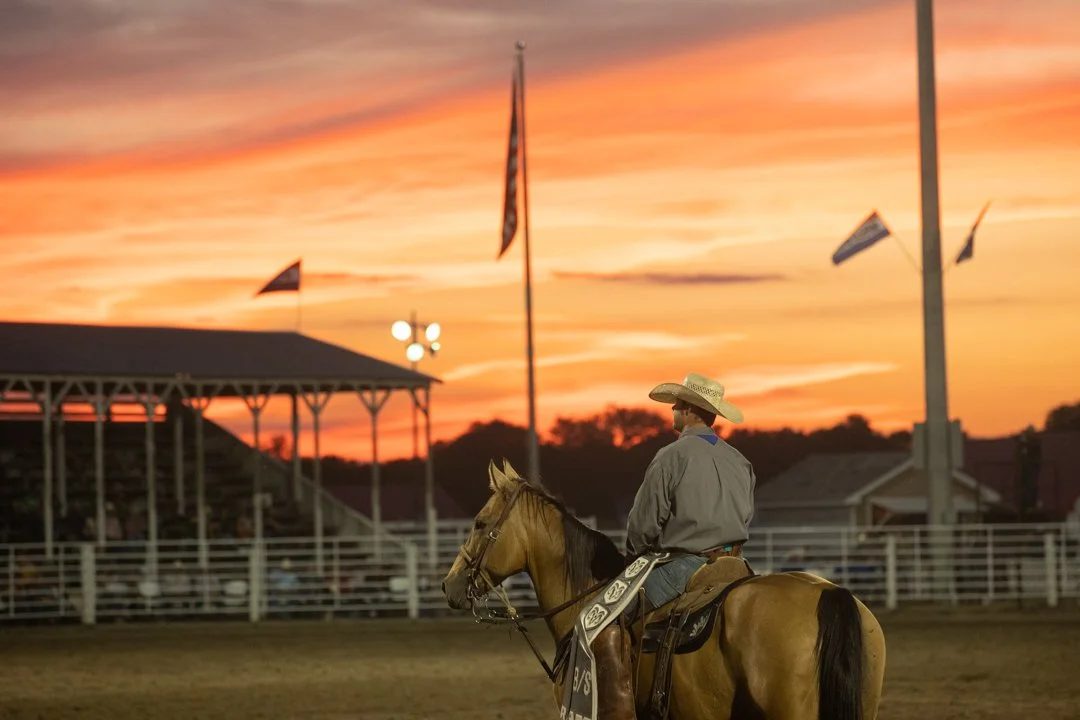 image of from the back of a cowboy on his horse in a rodeo arena at sunset, shot by commercial photographer Corey Rourke

