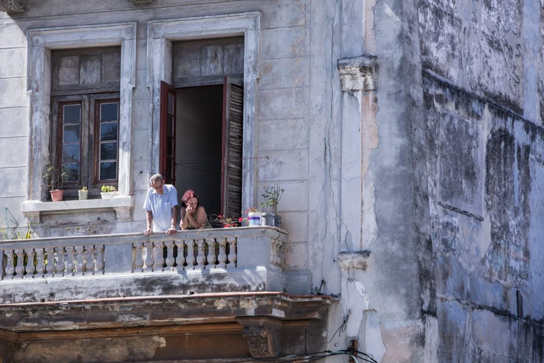older couple looking of the balcony of Havana Cuba home 
