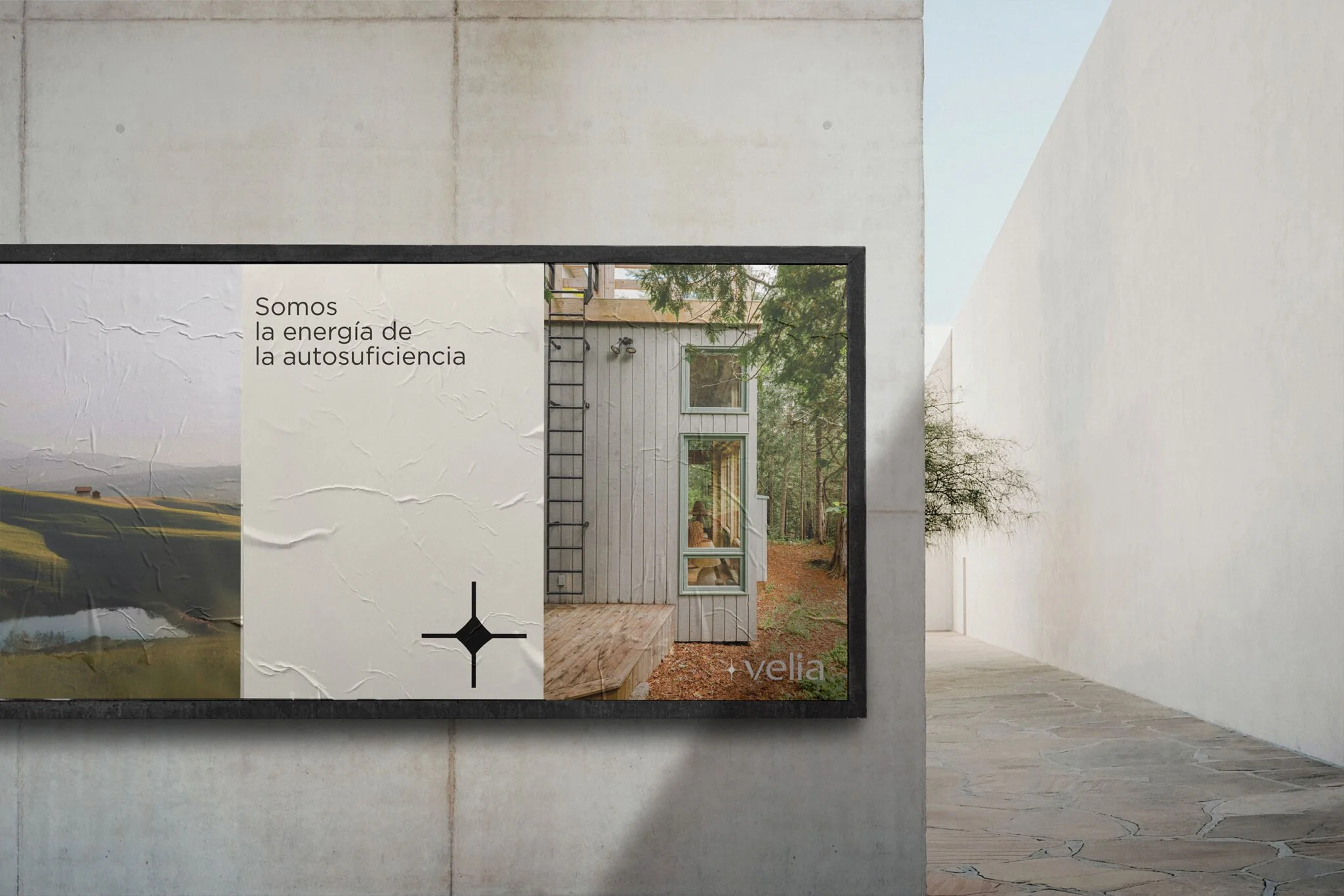 Cartel publicitario en un muro, que muestra un paisaje rural y una casa moderna con la frase "Somos la energía de la autosuficiencia". Al lado hay una imagen de un bosque.