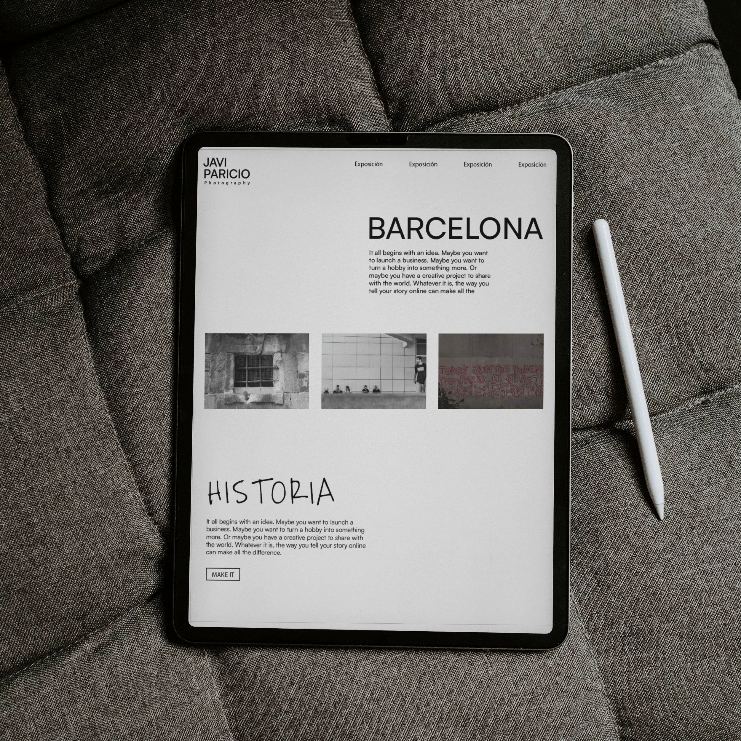 Pantalla de una tablet mostrando un portafolio de fotografía con el título 'Barcelona', fotografías en blanco y negro y texto en inglés, sobre un sillón gris con un bolígrafo blanco a la derecha.
