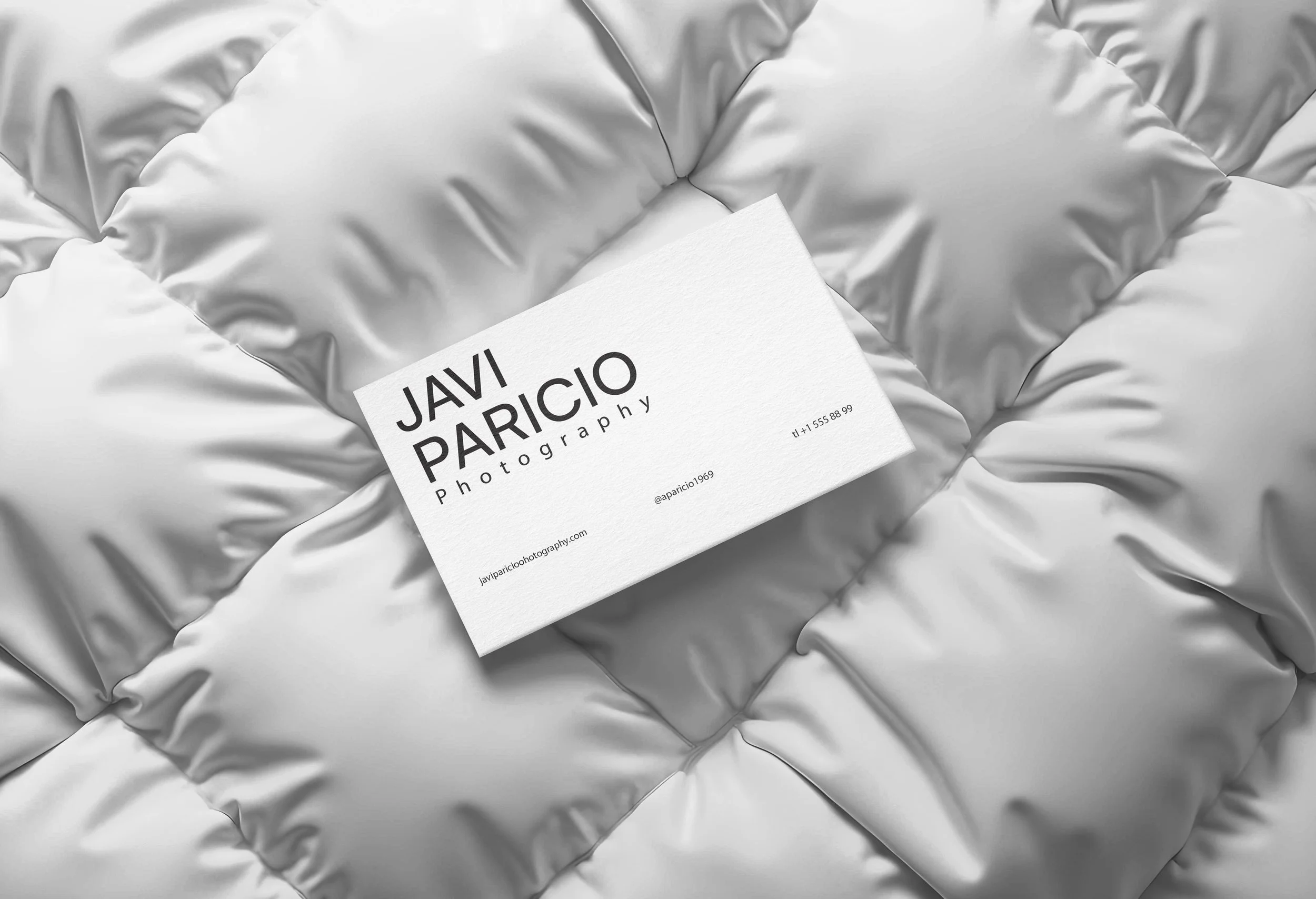 Tarjeta de presentación para Javi Paricio Photography sobre una superficie de edredón plateado.
