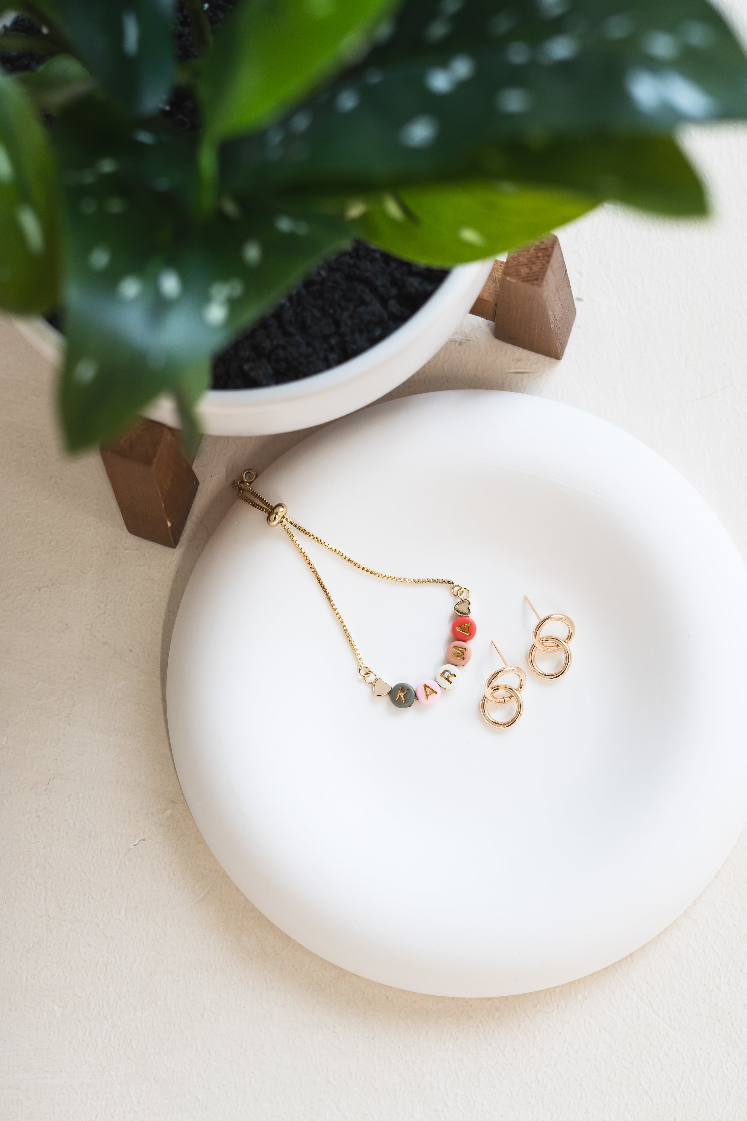 Overlooking handmade jewelry from Cambridge Ontario Canada in a dish beside a potted plant.