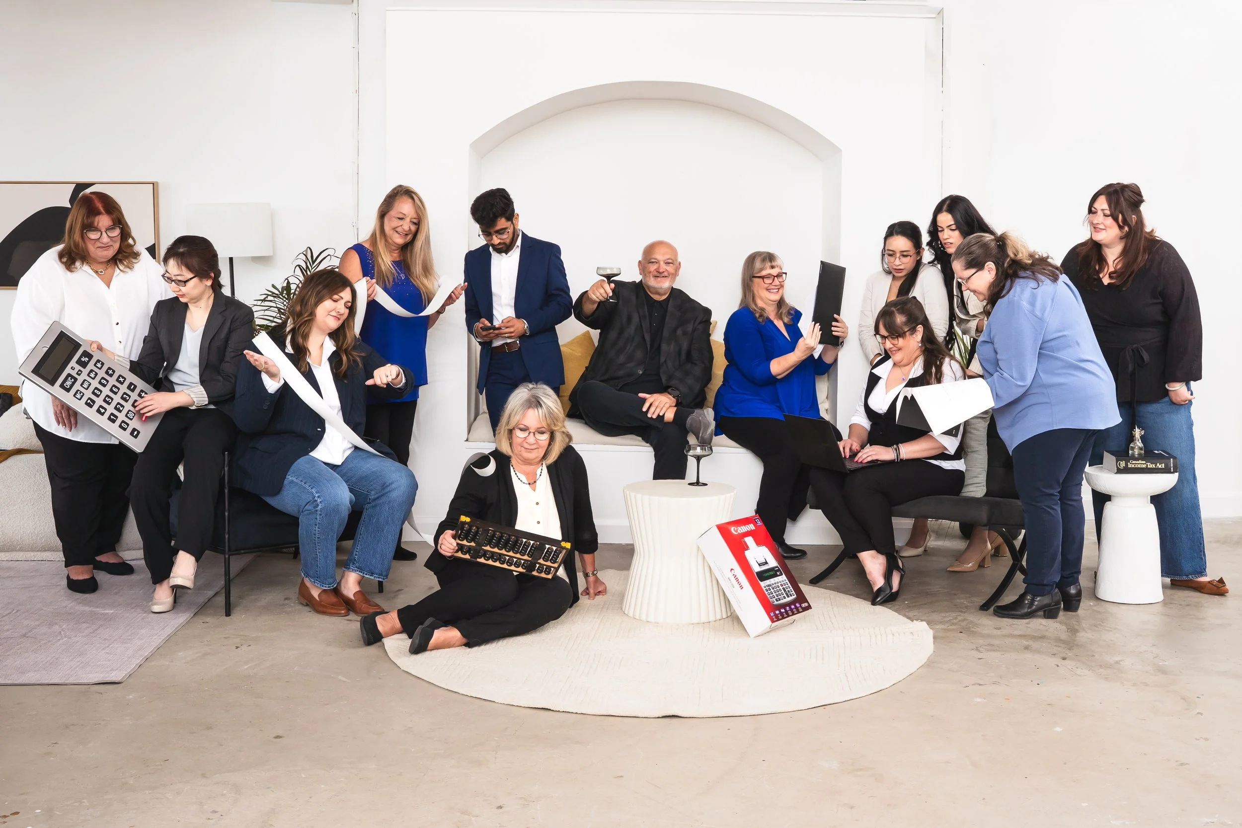 A Brand photographer's view of a Group of people gathered in a bright room, some sitting on a couch and others standing around, sharing a joyful moment with smiles, drinks, and conversation.