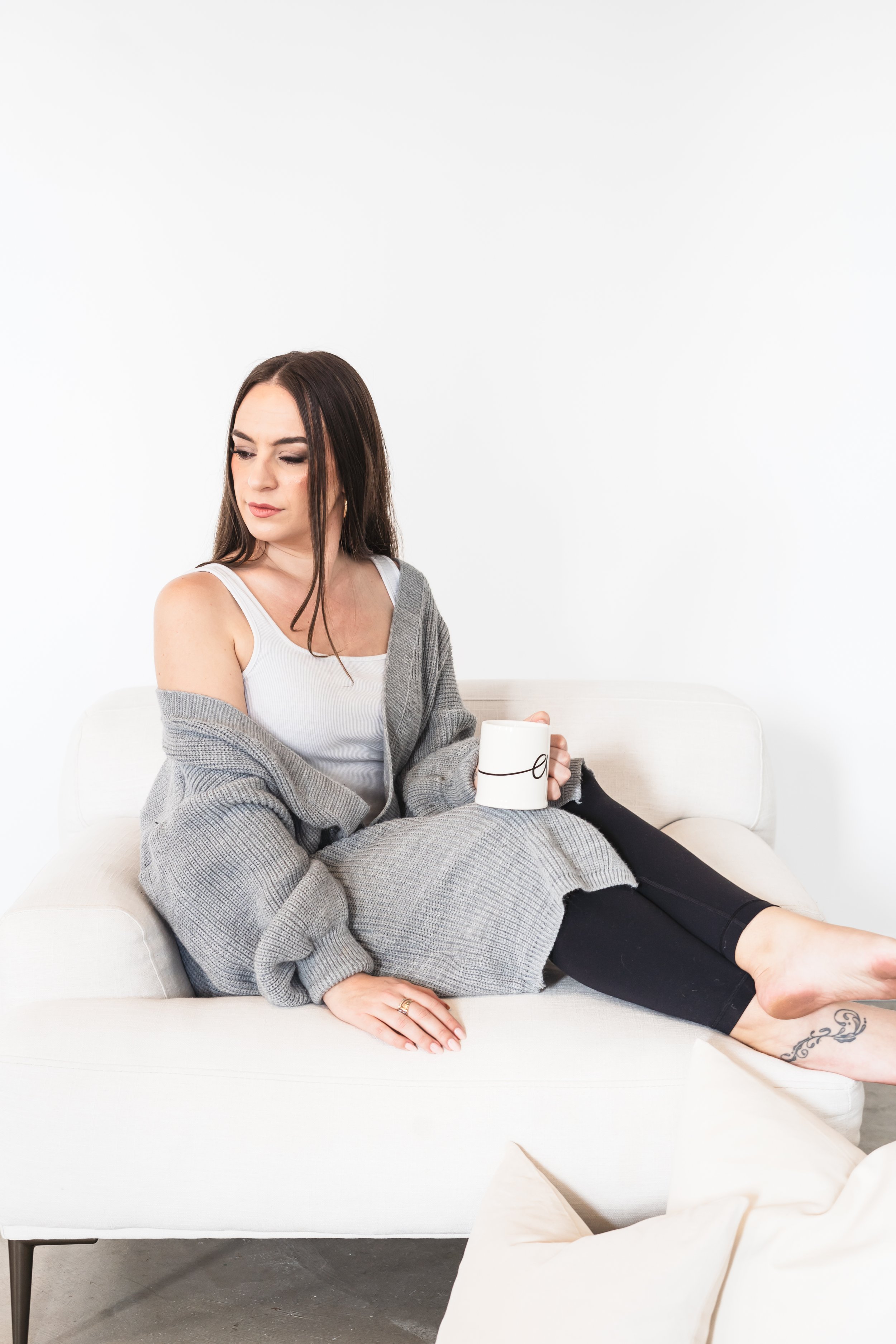 A consultant from Brantford Ontario Canada sitting in a white chair with a cup of coffee. She's looking down at the floor and off to the side.