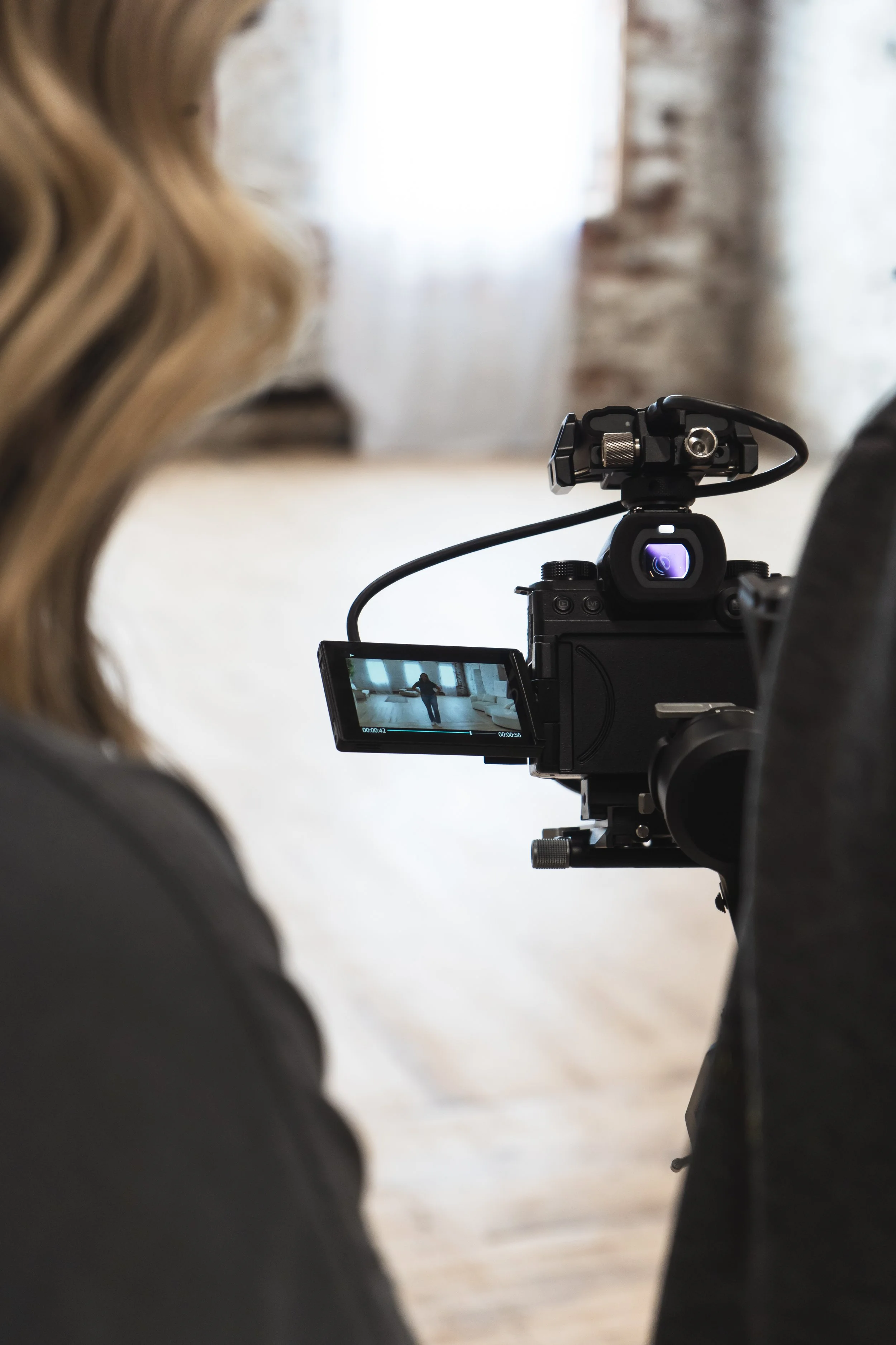 A brand photographer's view of the back of a videographer's lens in a studio in Burlington Ontario
