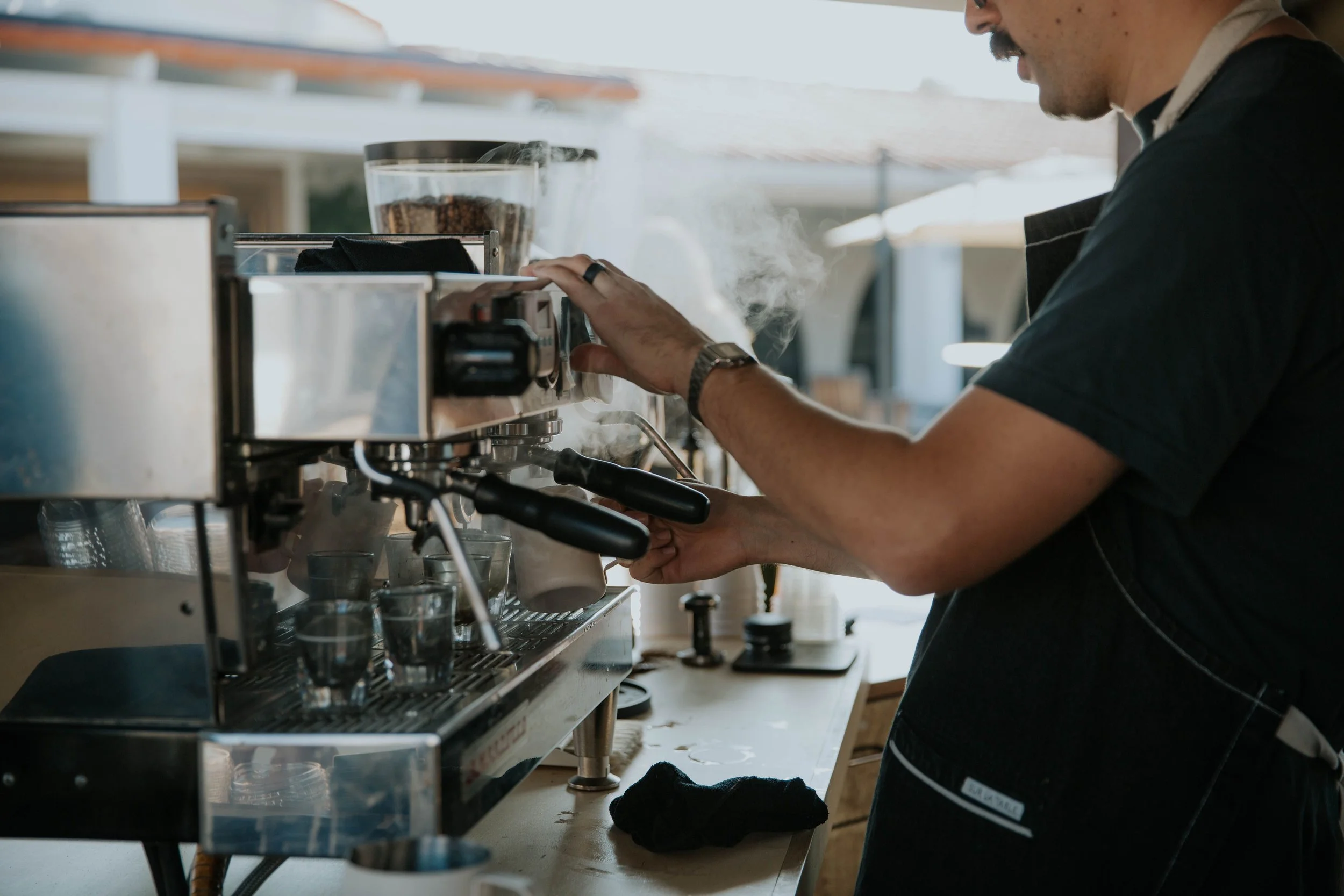 Barista operating an espresso machine in a coffee shop