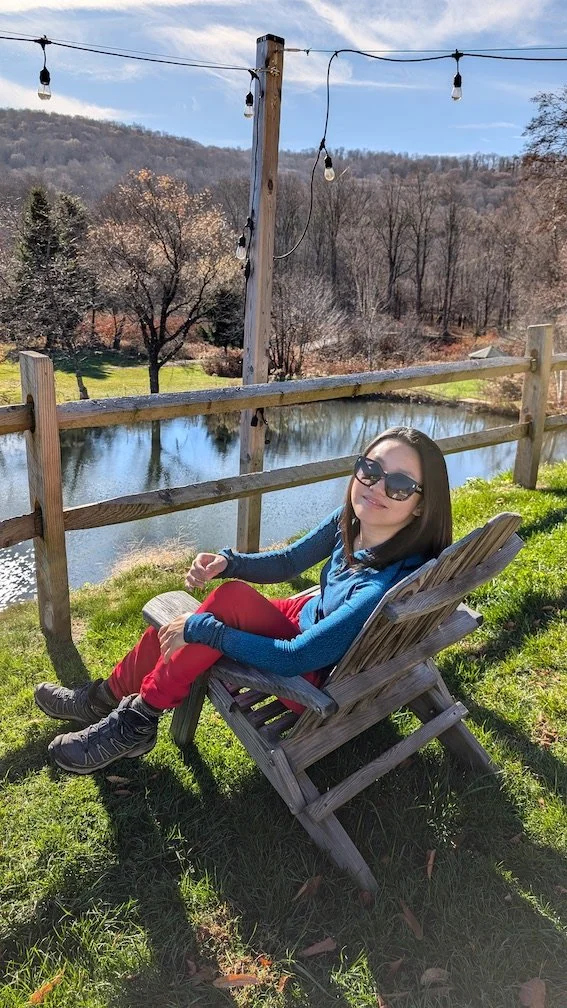 Judy Zhou sitting by a river at a hotel in the Catskills.