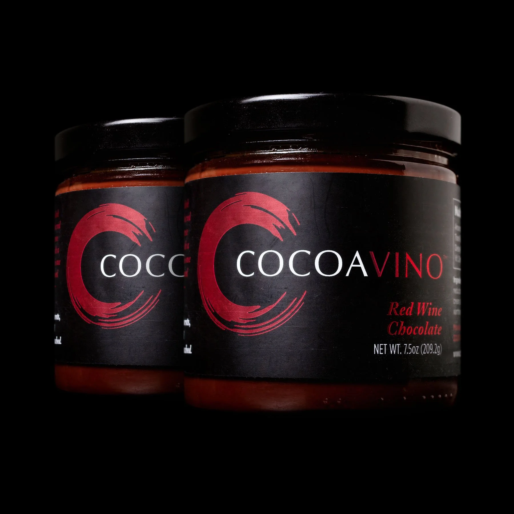 Two jars of Cocoavino Red Wine Chocolate against a black background, featuring the brand’s signature red and black label.