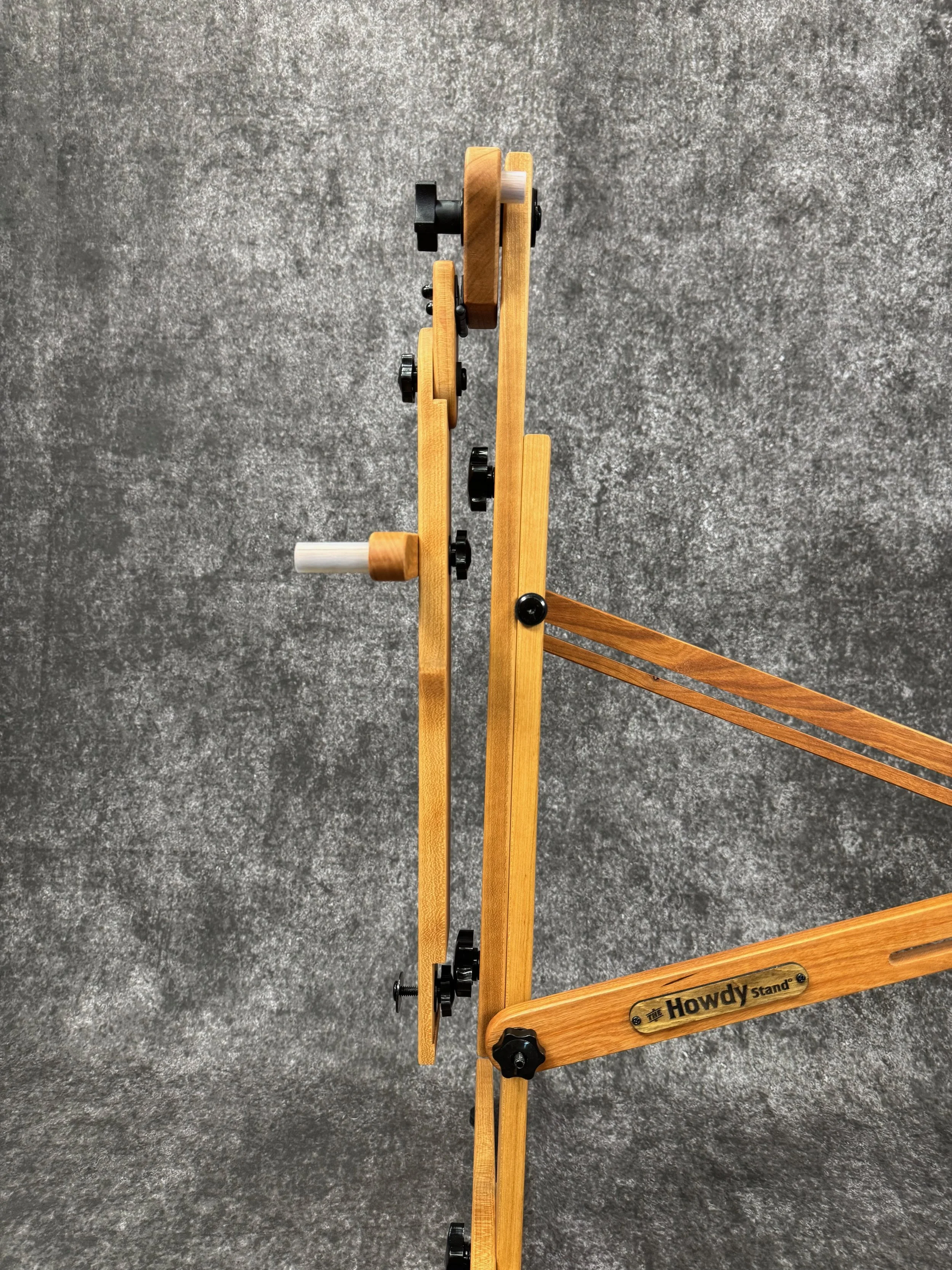 Close-up view of one side of a partially folded mountain dulcimer stand, labeled 'Howdy Stand'.