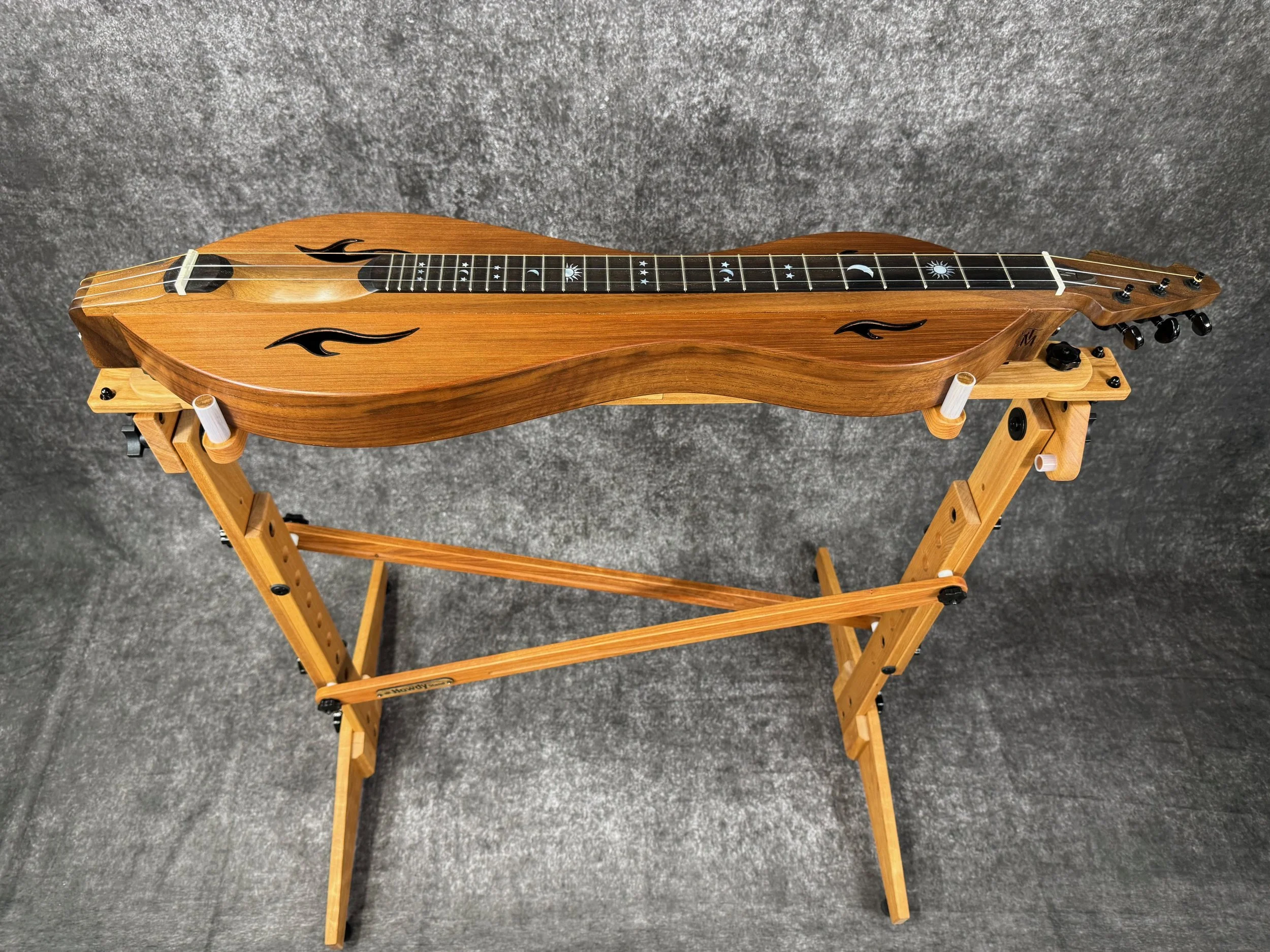 A top-down view of a mountain dulcimer on a wooden stand.