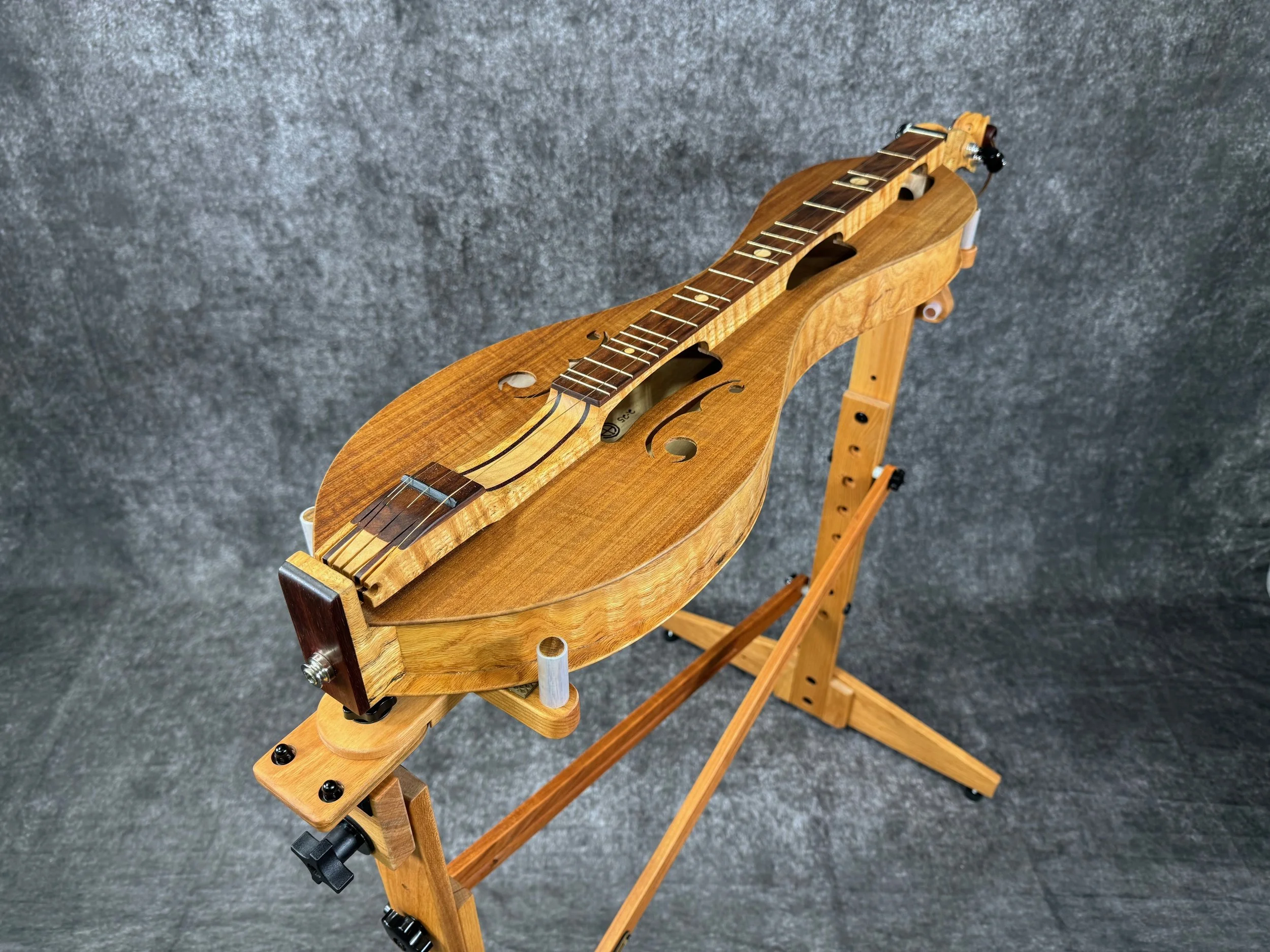A top-down view of a mountain dulcimer on a wooden stand.