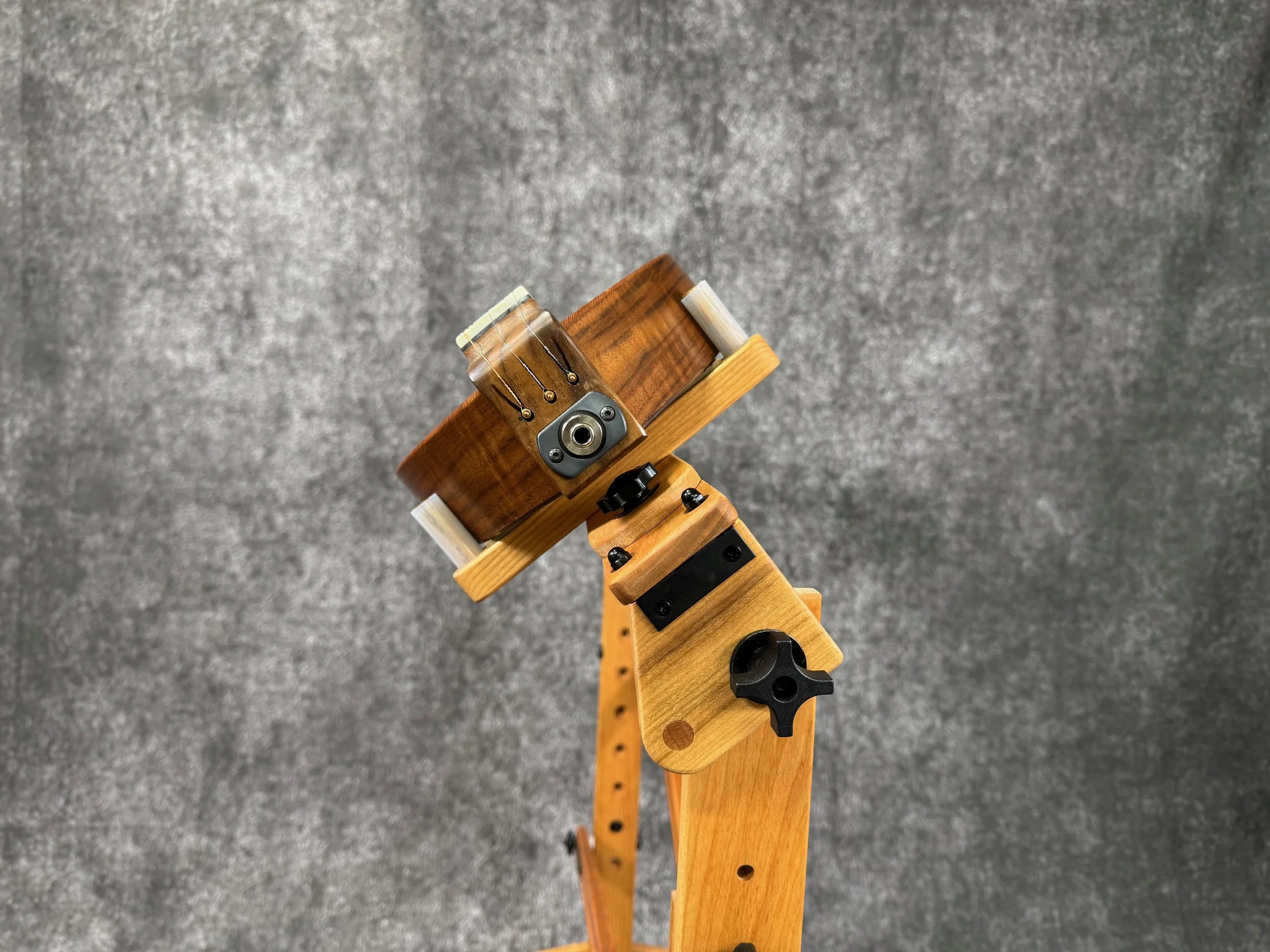 Close-up of tailblock and electric pickup jack at the end of a mountain dulcimer, placed on a wooden stand and tilted.
