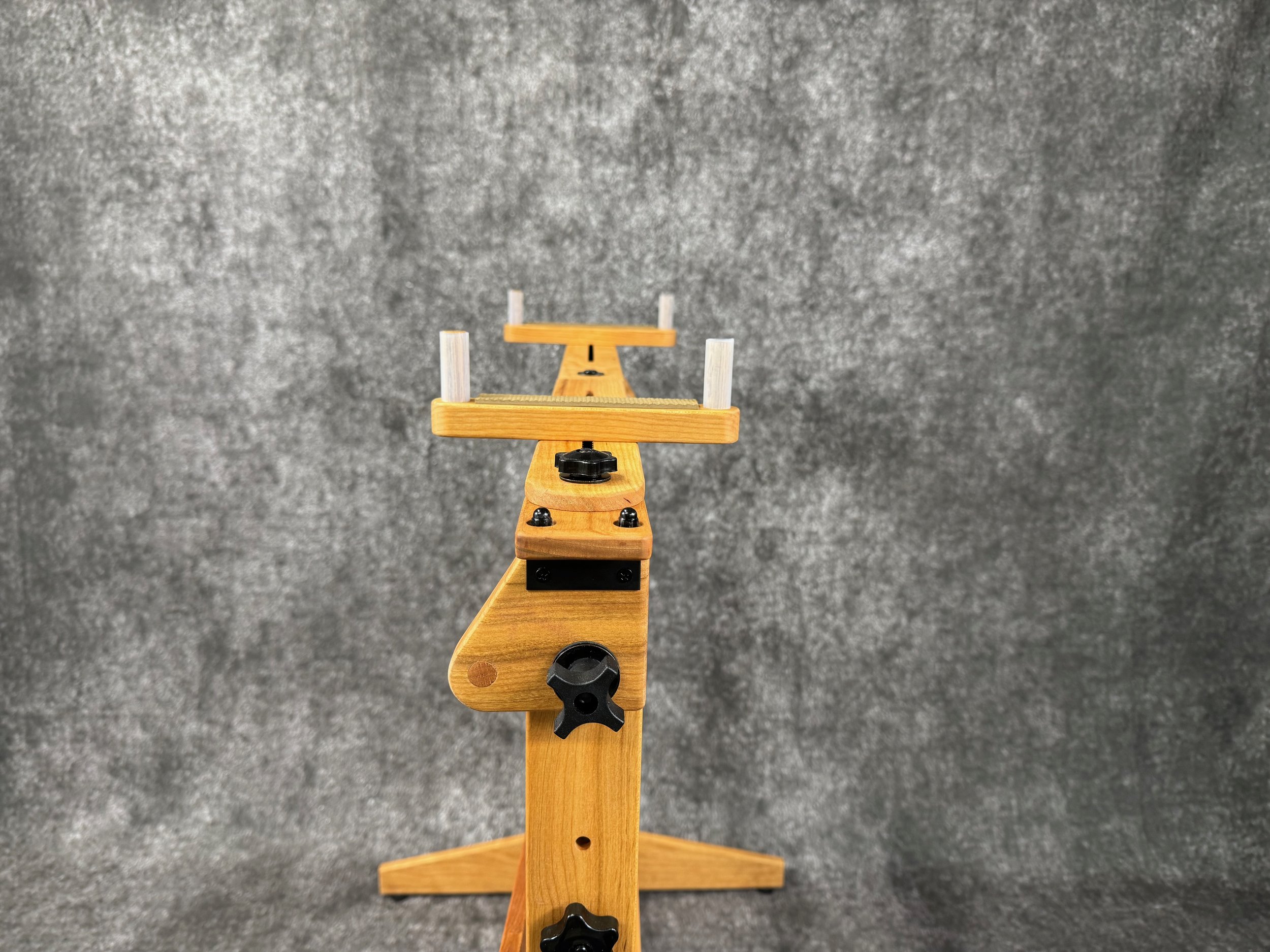 A straight end-view of a mountain dulcimer player's stand, with black knobs, in solid cherry wood.