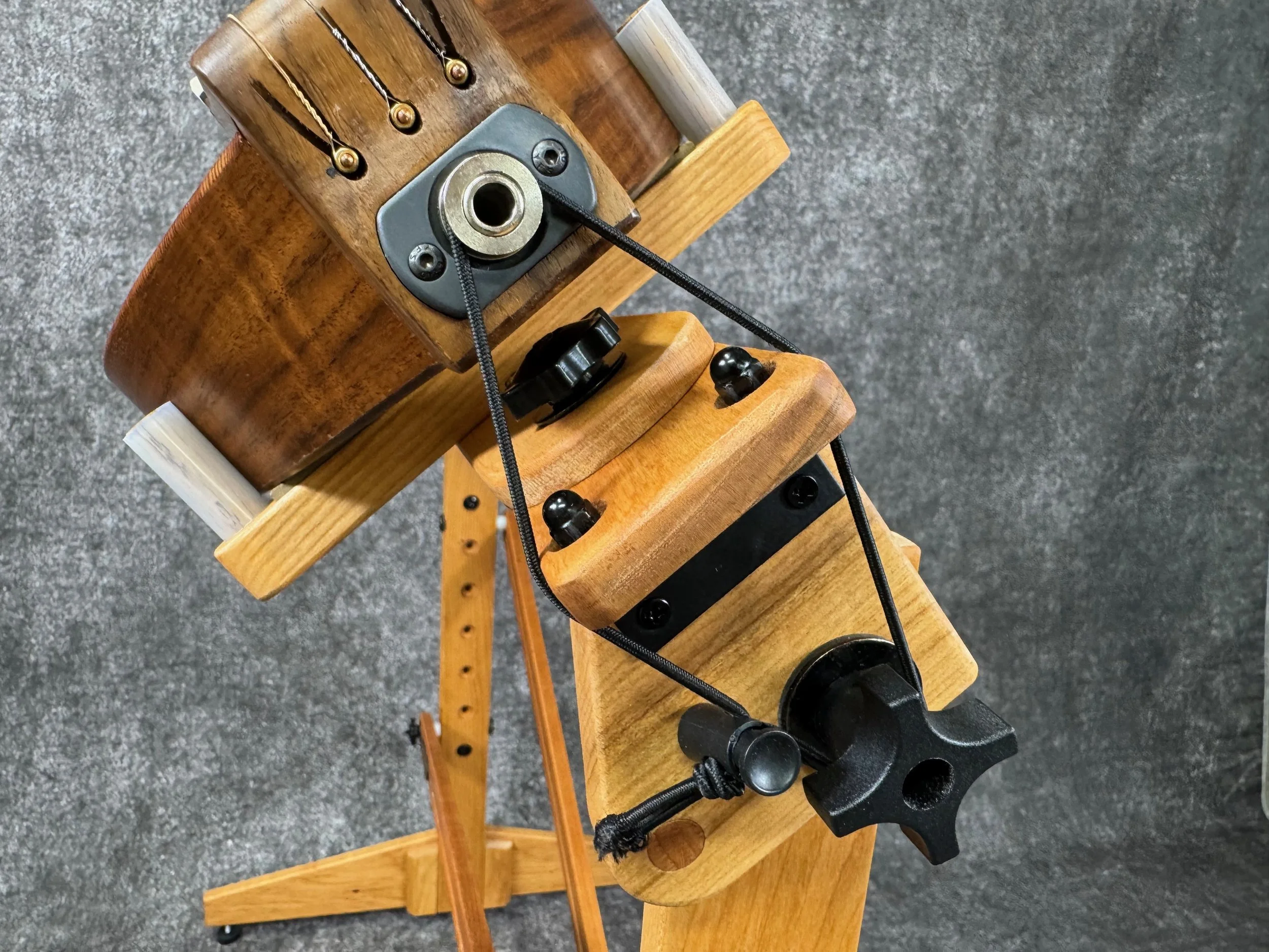 Close-up of tailblock and electric pickup jack at the end of a mountain dulcimer, placed on a wooden stand and tilted.