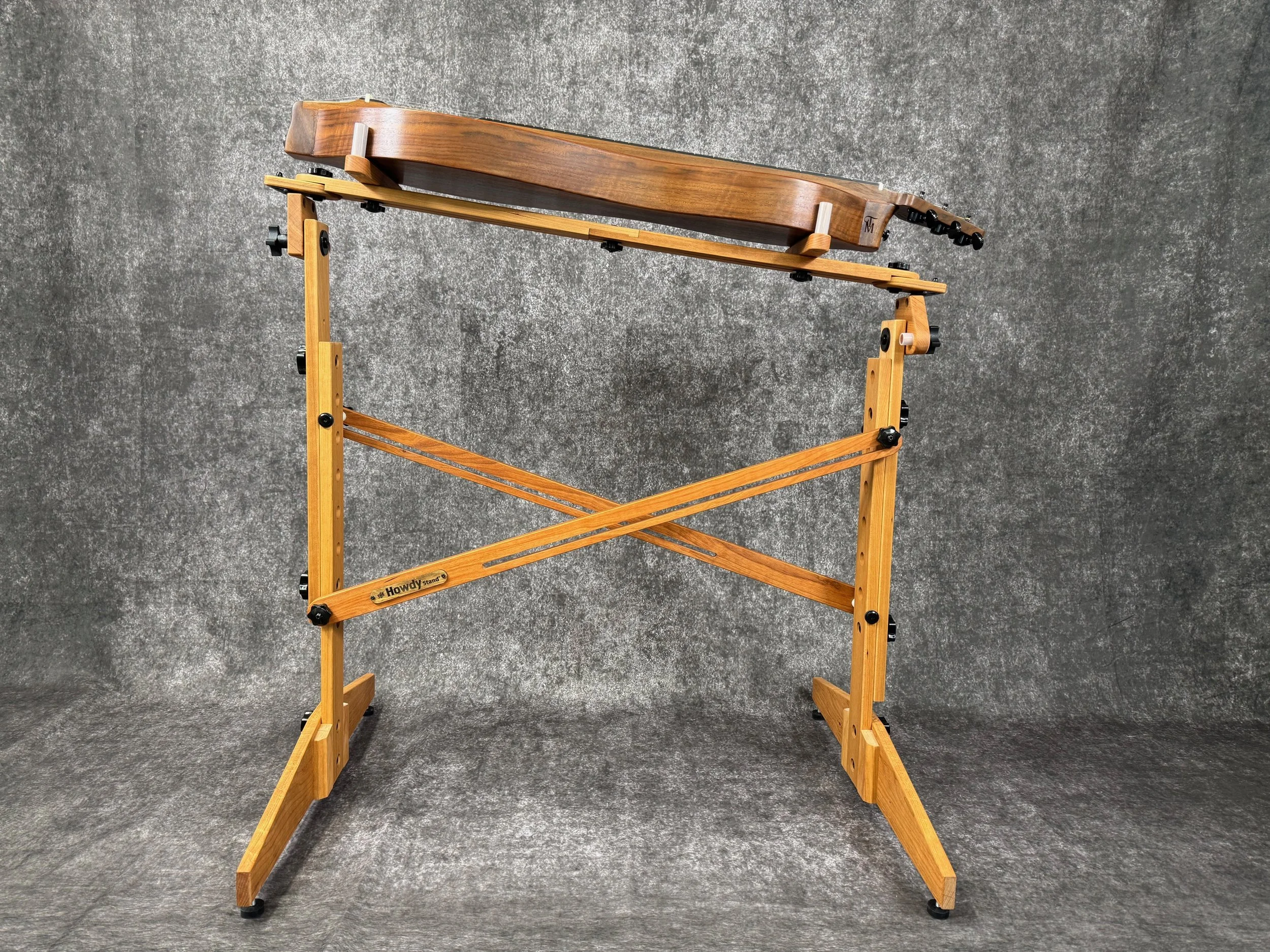 A mountain dulcimer, on a wooden stand, with one end angled down.