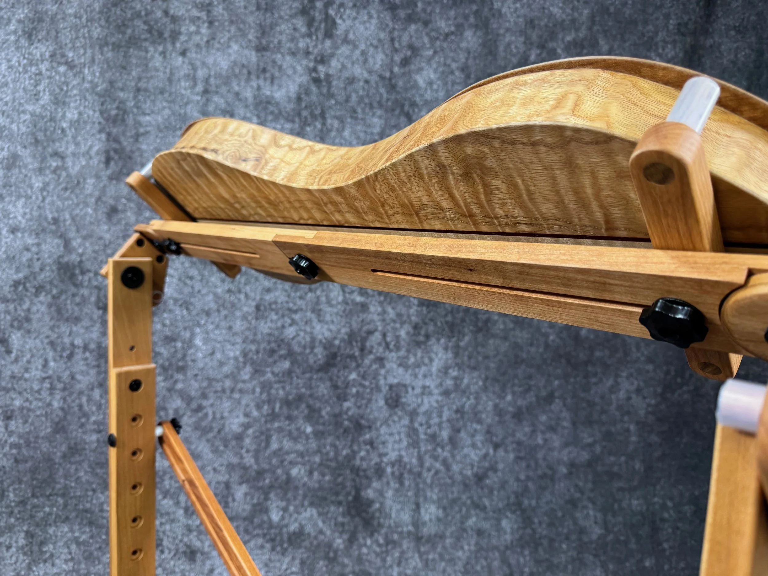 A bottom-up view of a mountain dulcimer on a wooden stand, tilted away from the camera.