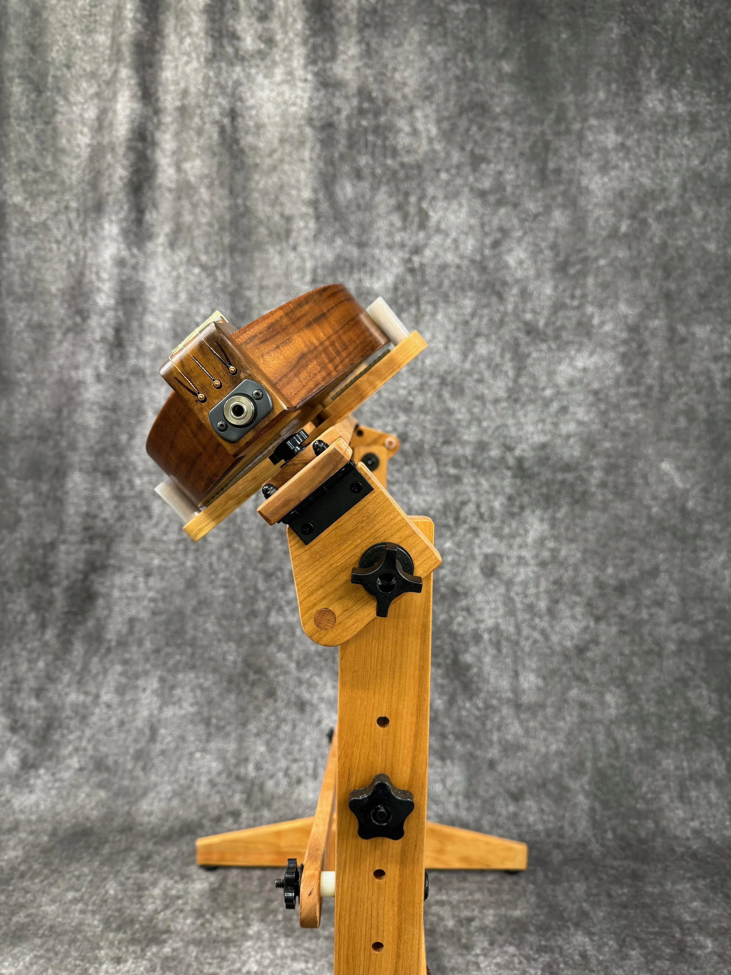 A mountain dulcimer on a dulcimer stand, shown tilted.