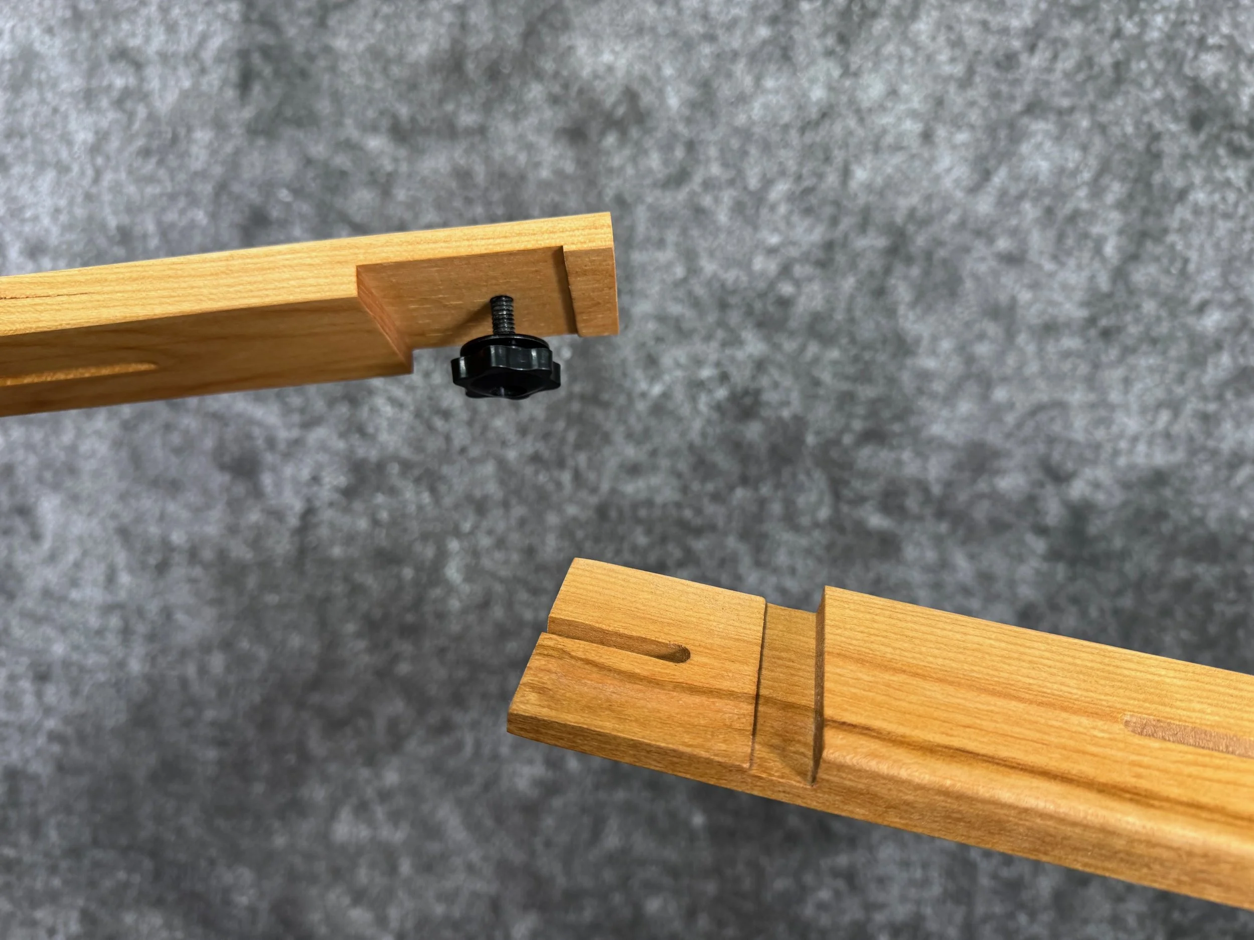 Close-up of two-piece lap-loc wooden joint, with a black screw and plastic knob.