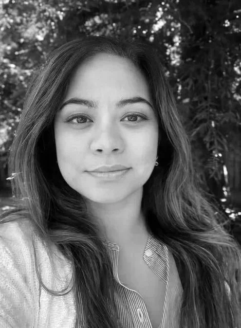 picture of Tasha Monserrat, a woman with dark colored long hair, wearing a white sweater with a dark colored shirt underneath; photo is in black and white