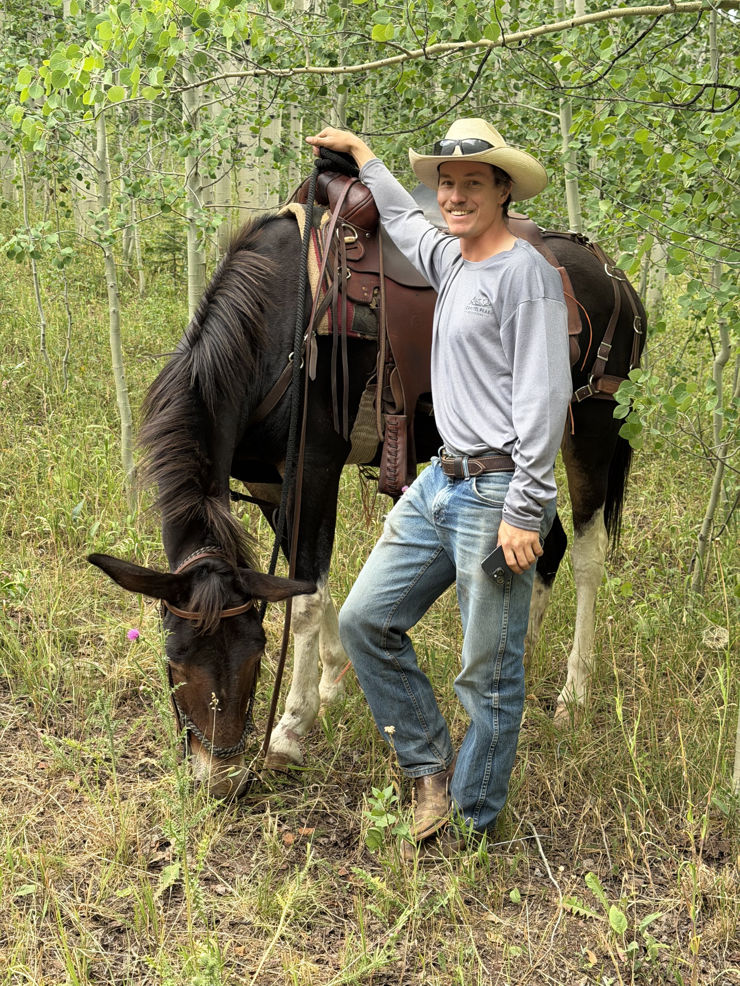 Ted Benge smiling with a mule in the aspen trees near Aspen / Snowmass on a horseback ride