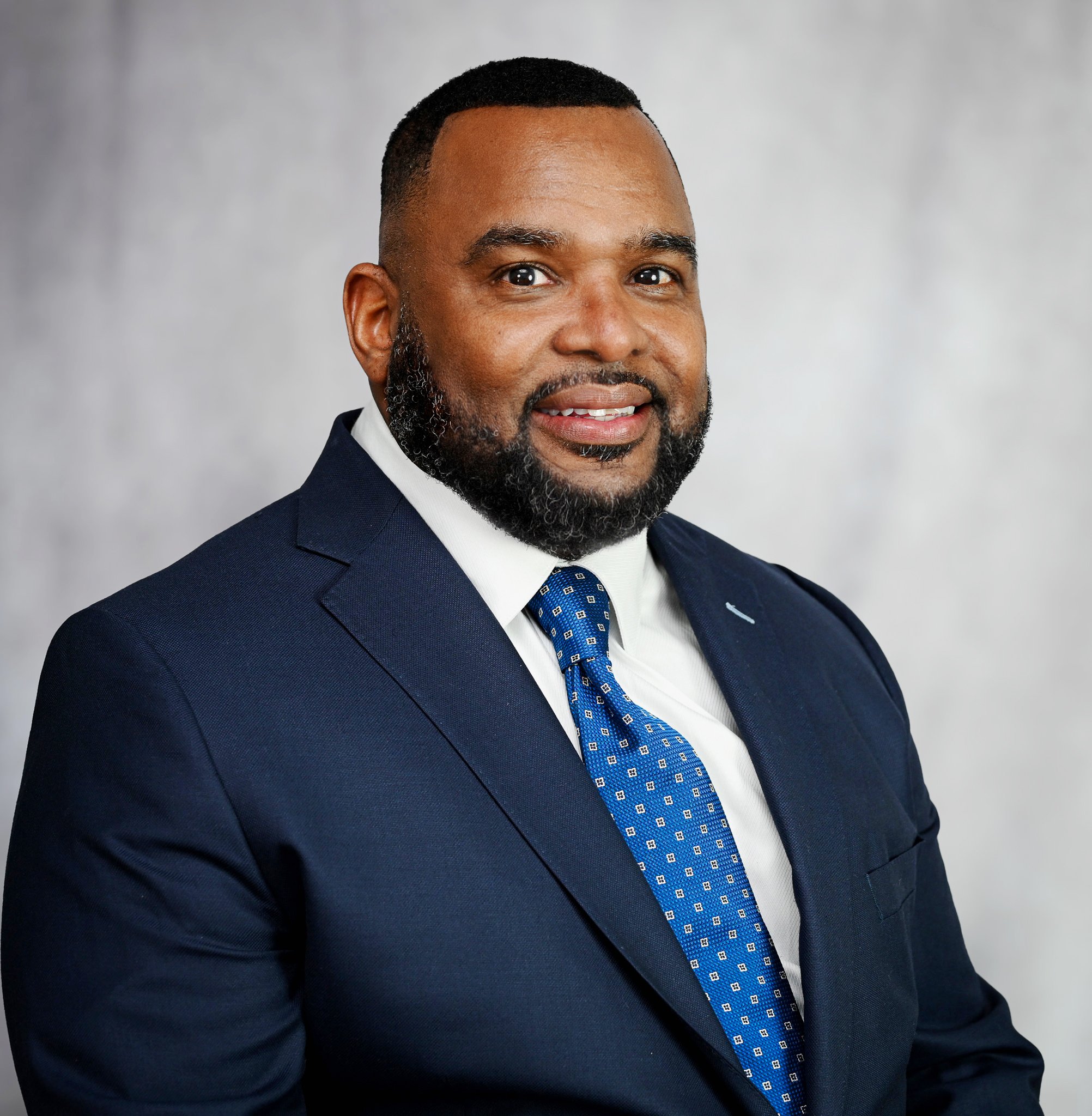 "Man wearing a navy suit and tie, captured during a professional headshot photography session."