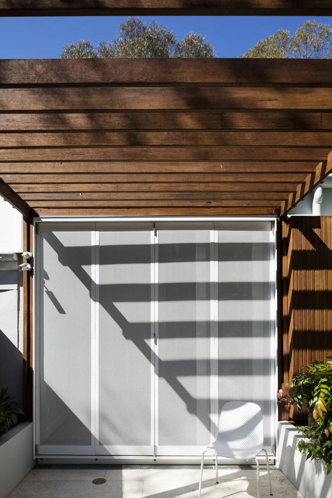Outdoor wooden pergola casting shadows on the bifold screens