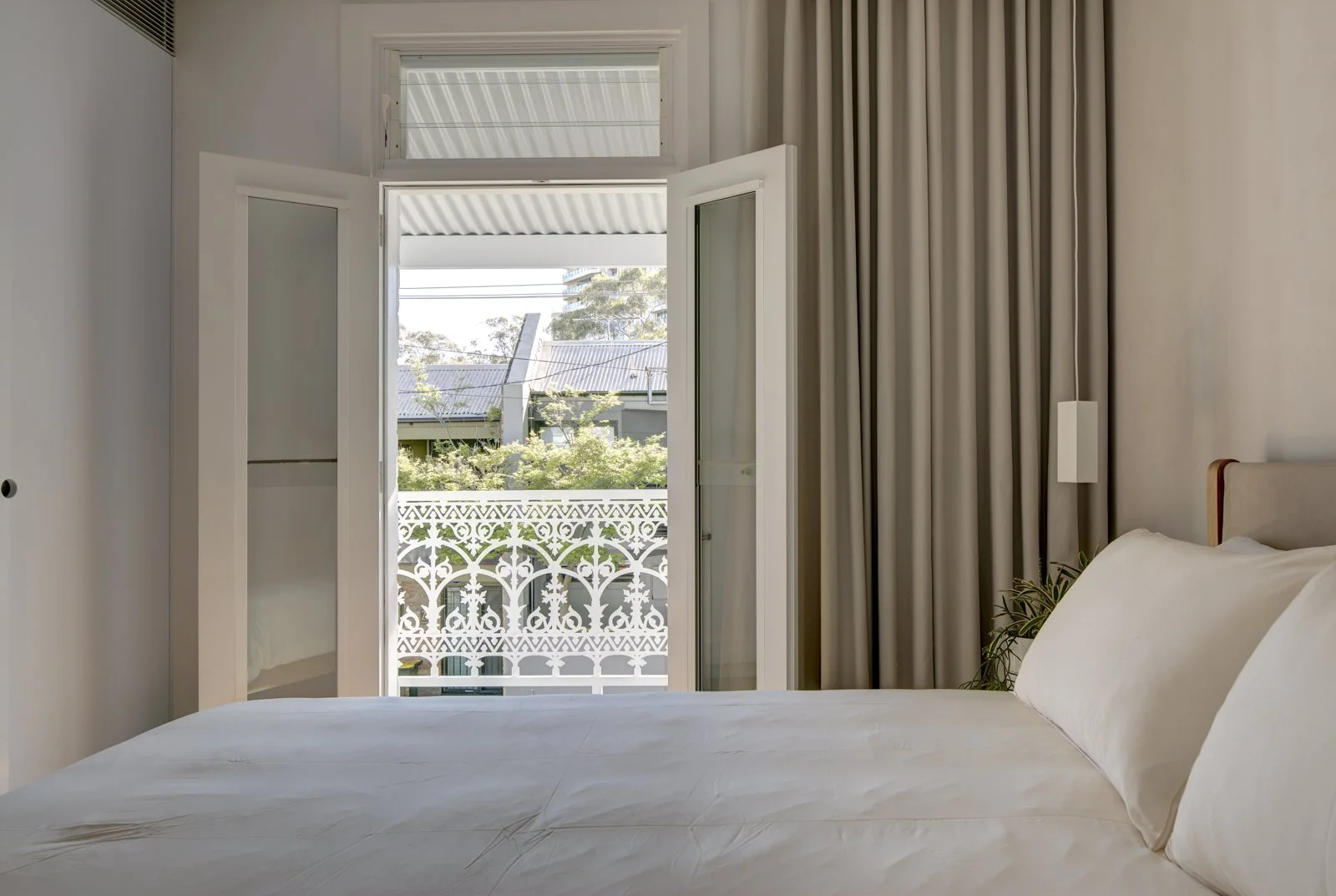 Bedroom interior with a bed and open double doors leading to a balcony with decorative railing.