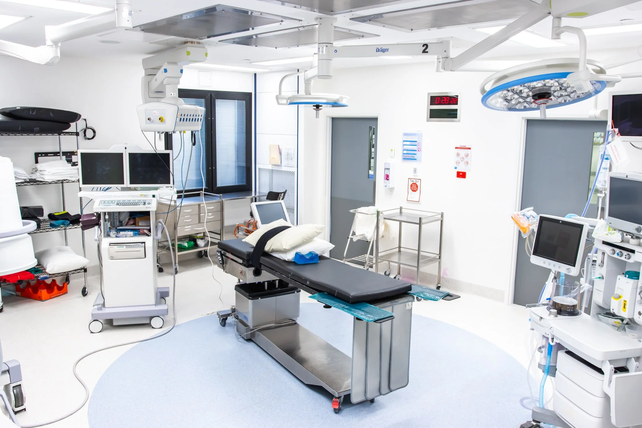 An empty hospital operating room with surgical equipment, medical monitors, and an operating table in the center.