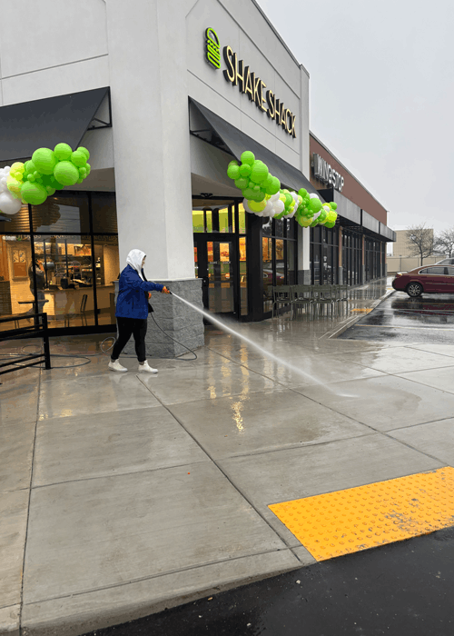 Evelyn using a power washing to concrete clean Shack Shack's concrete back into shape!