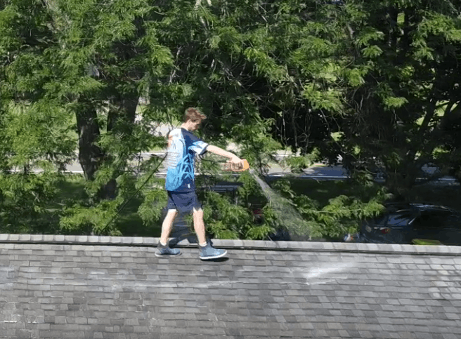 Adam from Lansing Precision Power-Wash performing a professional roof cleaning on a shingle roof.