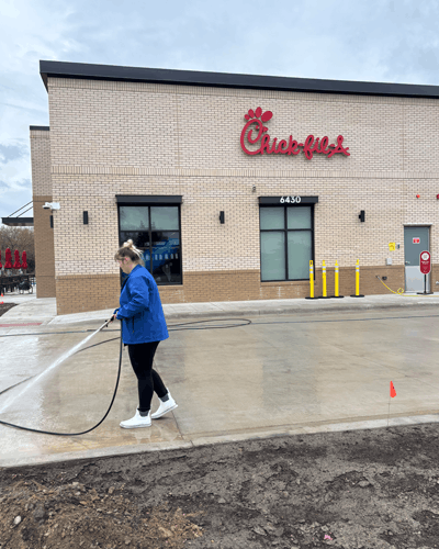 Evelyn from Lansing Precision Power-Wash standing on wet concrete from some concrete cleaning we did at Chik-Fil-A in Lansing, Mi